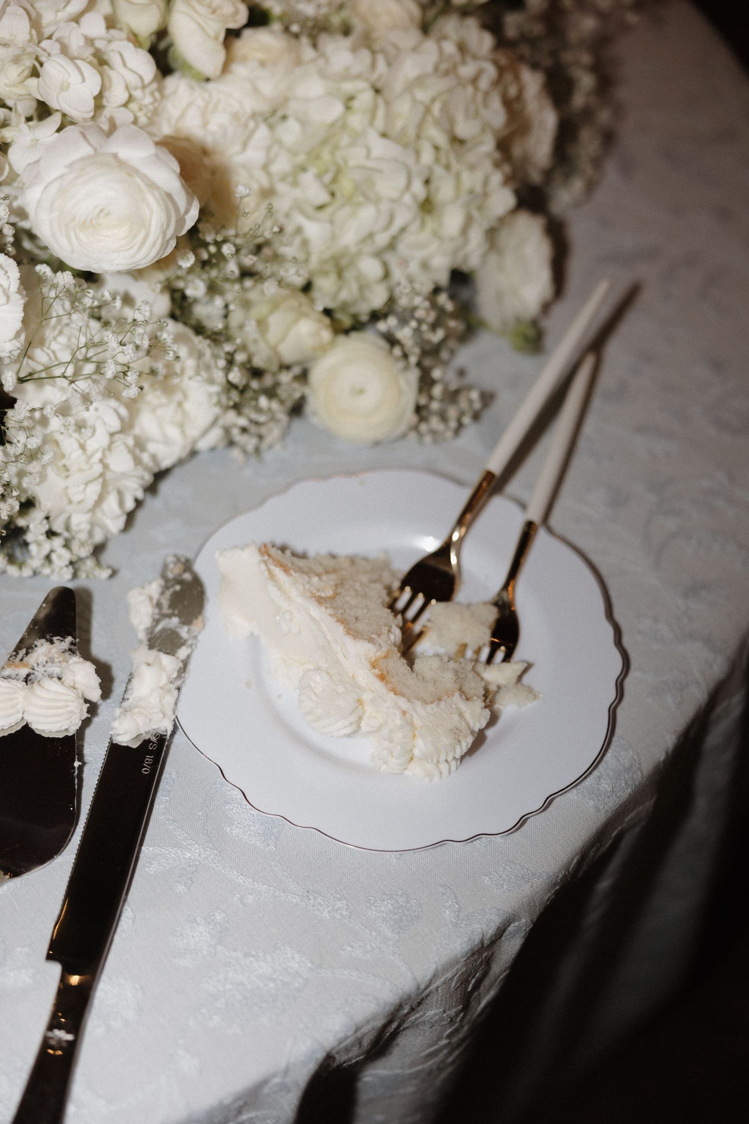 A series of photos showing white wedding cake being served with silver utensils next to elegant floral arrangements.