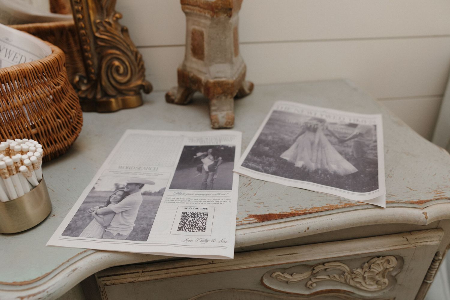 A collection of black and white photographs and documents spread across a table with decorative objects nearby.