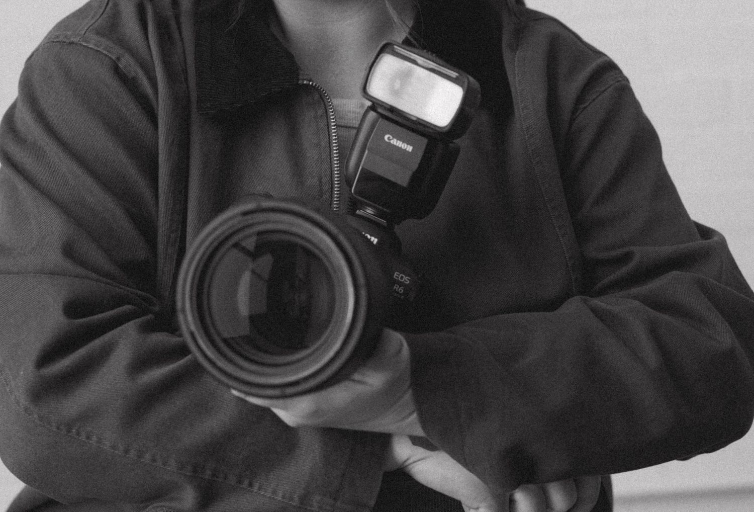 Black and white portrait of someone wearing headphones and a dark jacket while looking at the camera.