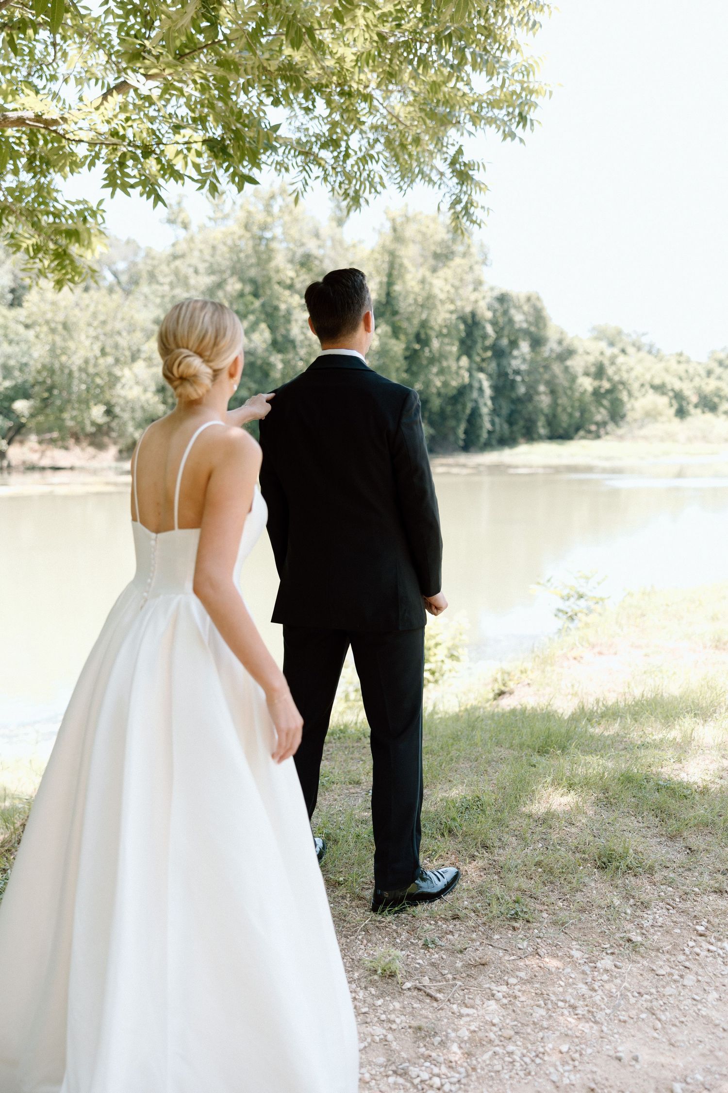 A bride and groom walk along a scenic lakeside path during their wedding photo session.