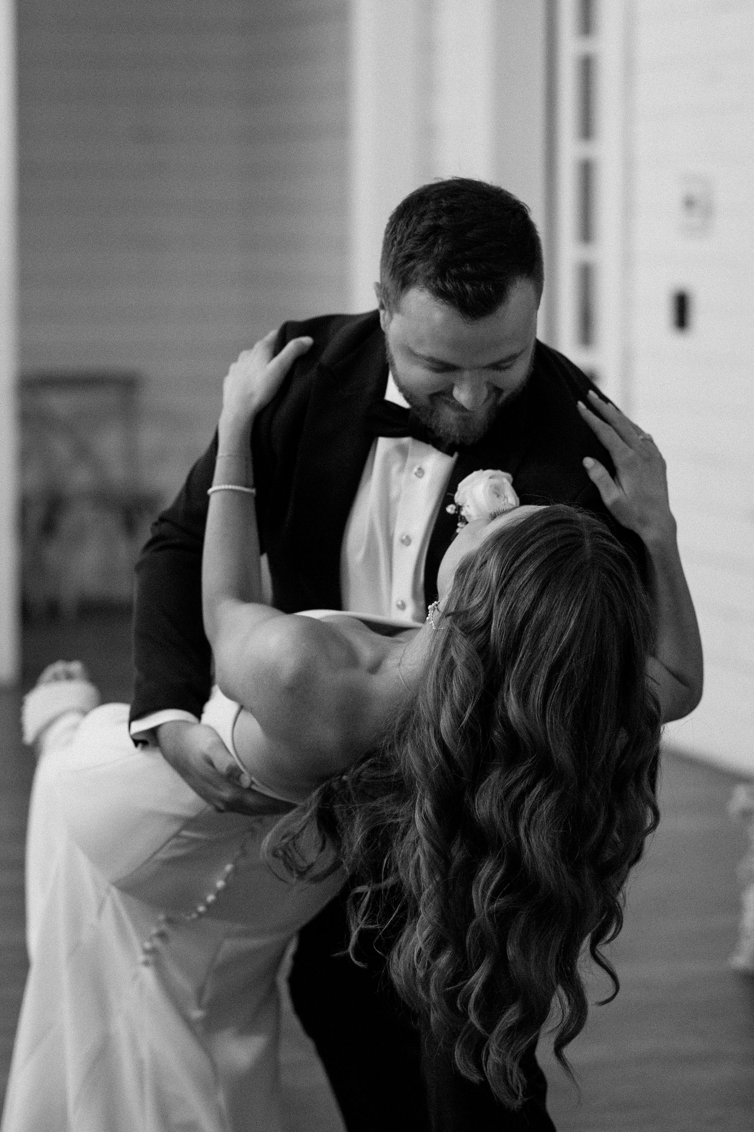 A romantic black and white photo series showing a couple sharing intimate kisses in a columned hallway.
