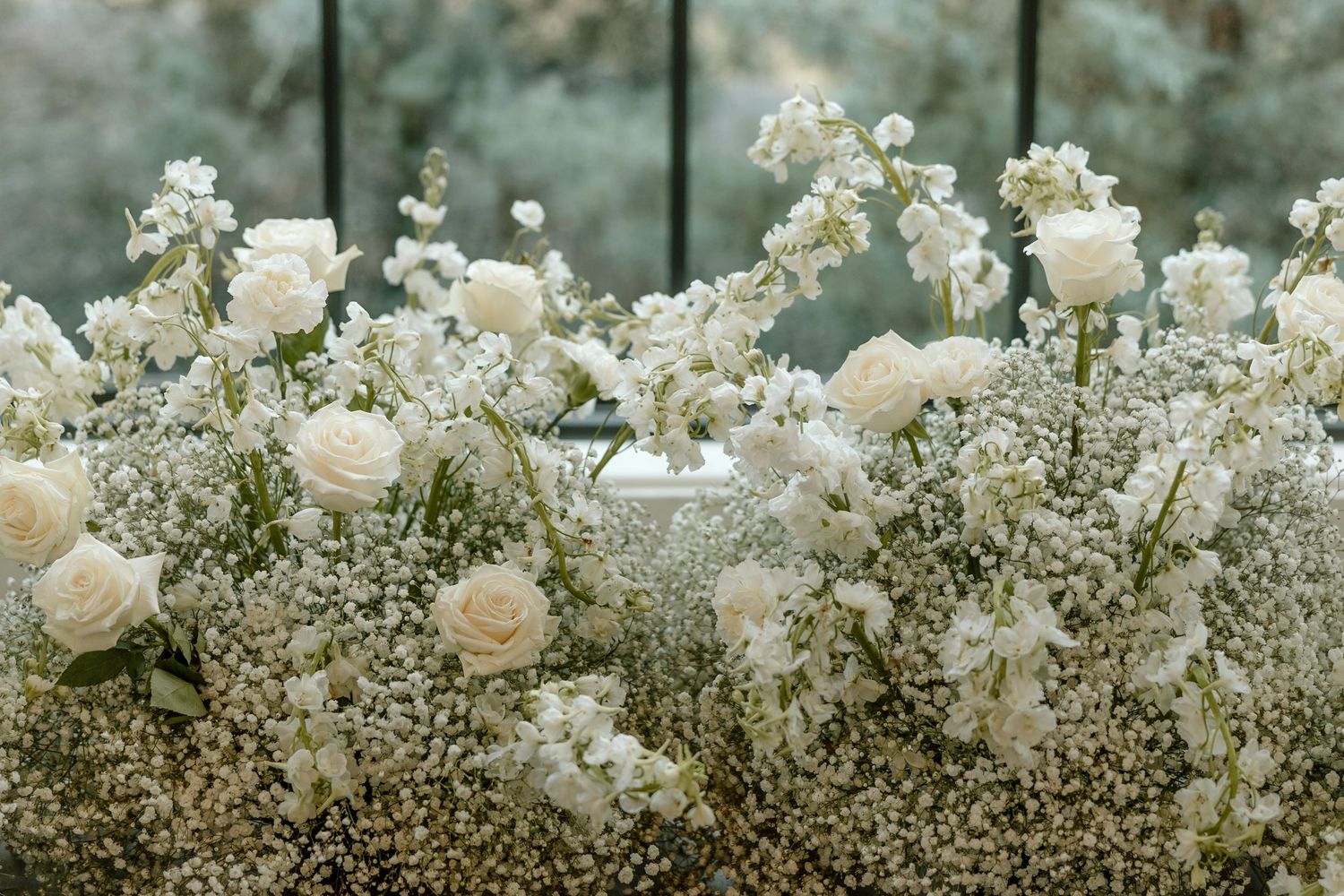 Delicate white baby's breath flowers and roses create a romantic floral arrangement against a soft blurred background.