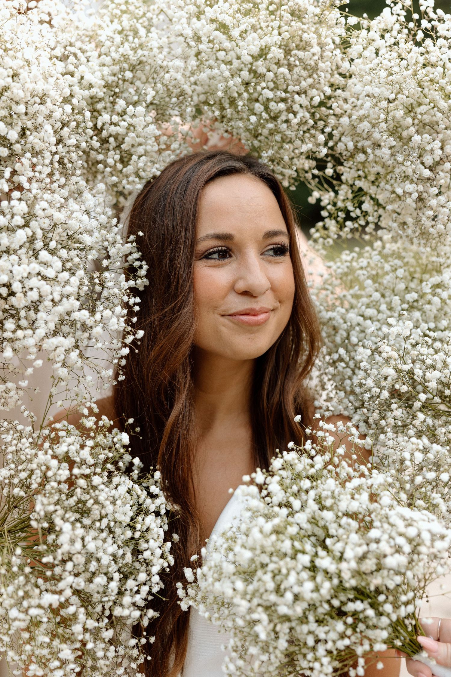 A portrait framed by delicate white baby's breath flowers against a natural outdoor background.
