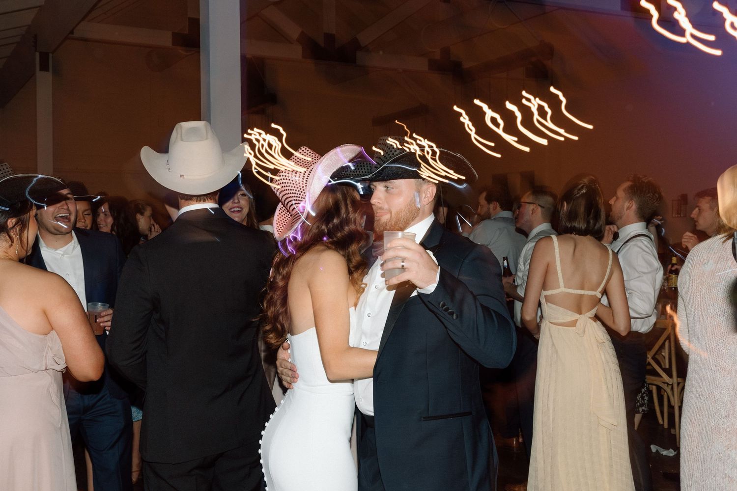 Couples dancing at an elegant wedding reception with decorative lighting creating a romantic atmosphere.