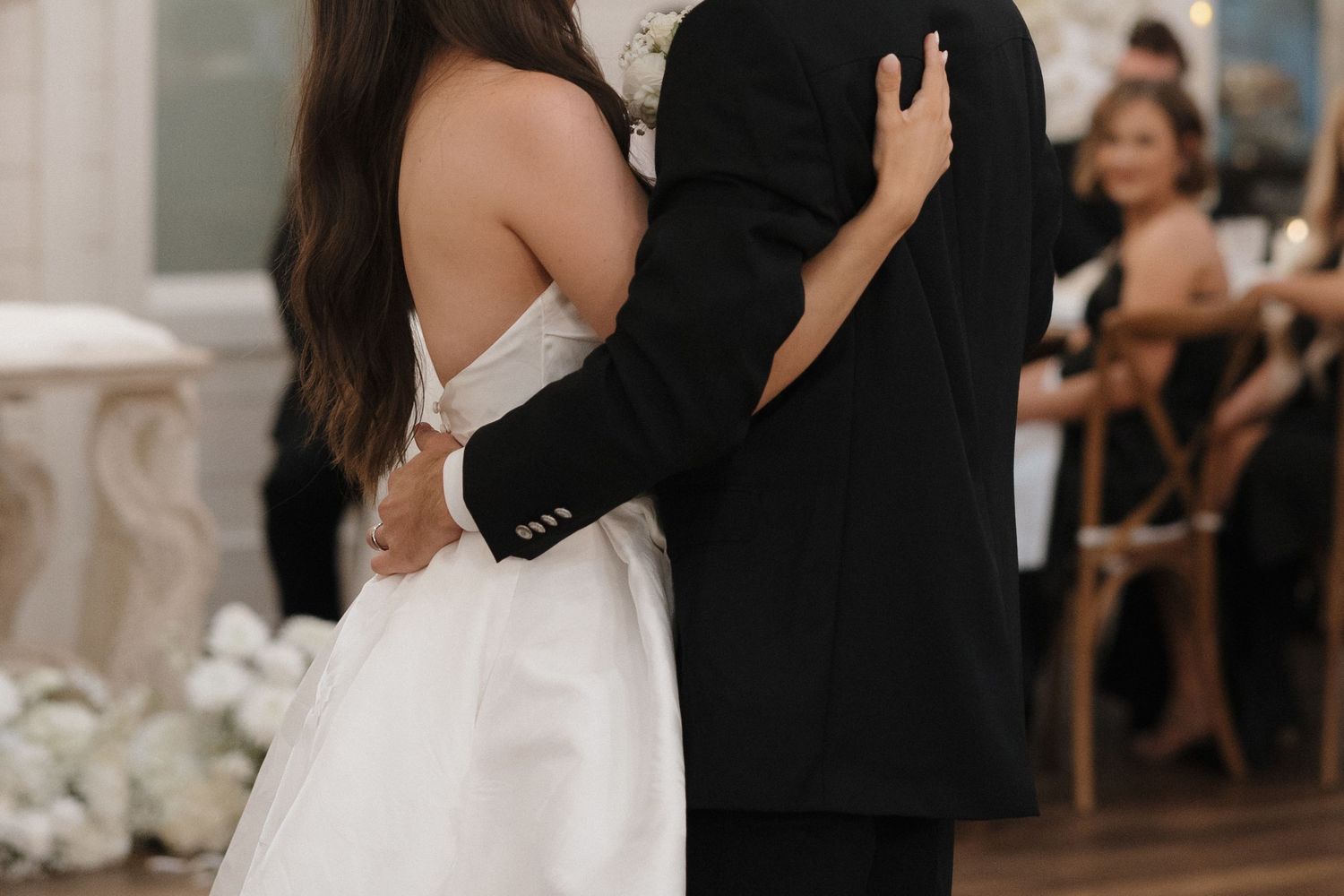 Bride and groom share a romantic dance at their wedding reception surrounded by guests and elegant decor.