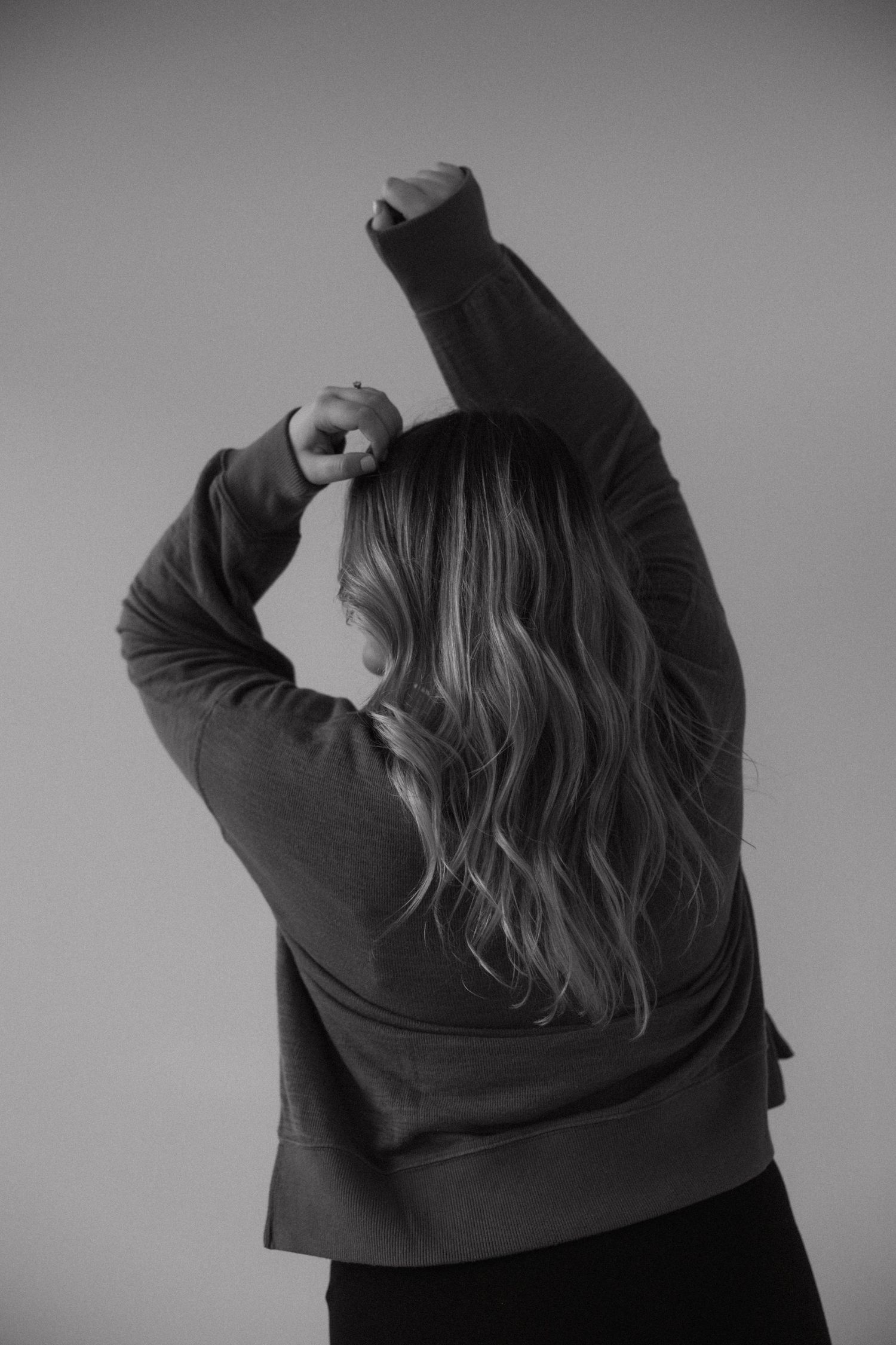 Artistic black and white portrait showing someone in a dark sweater from behind.