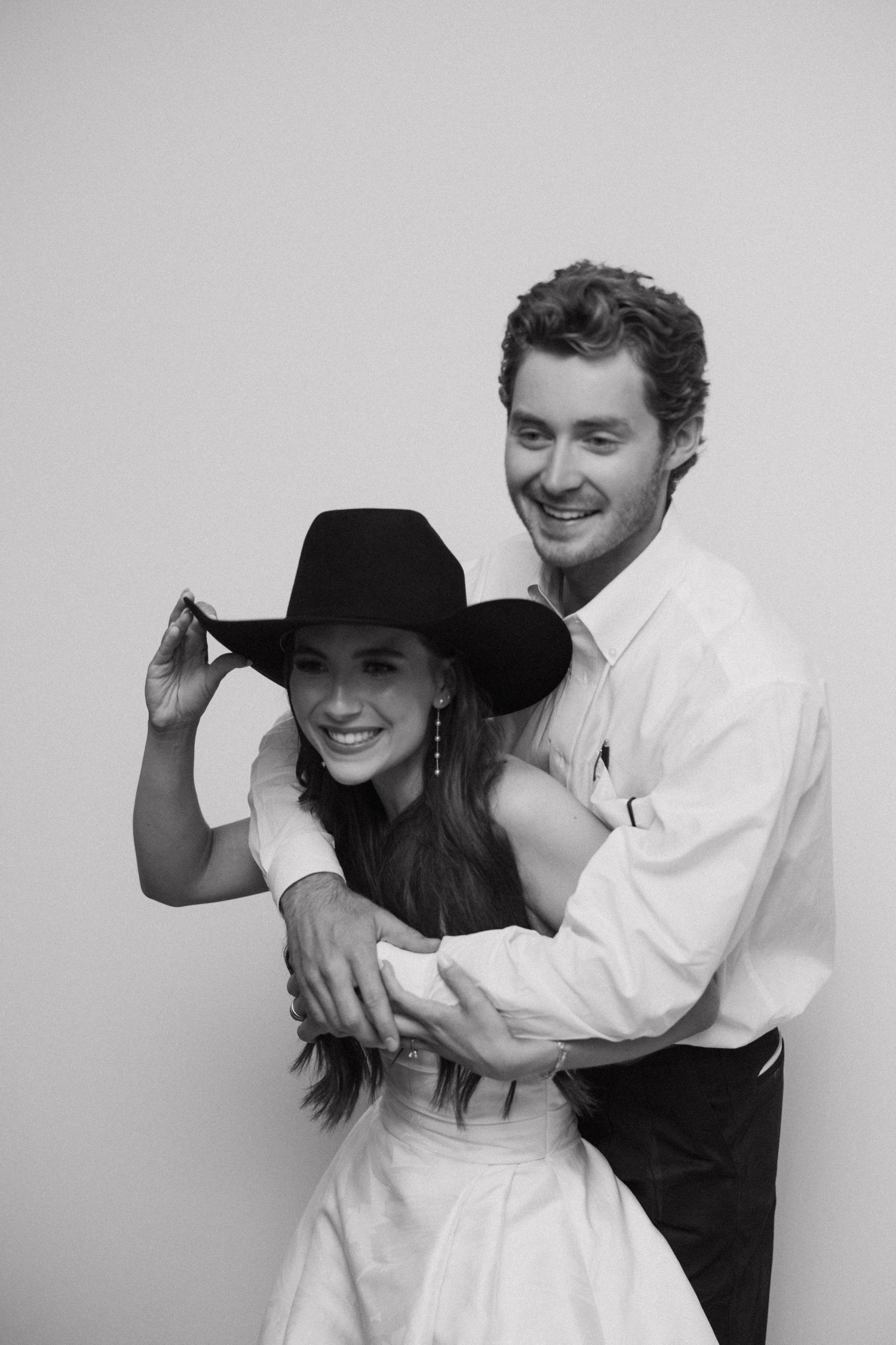 Black and white photo series showing playful poses between two people in casual attire against a light background.