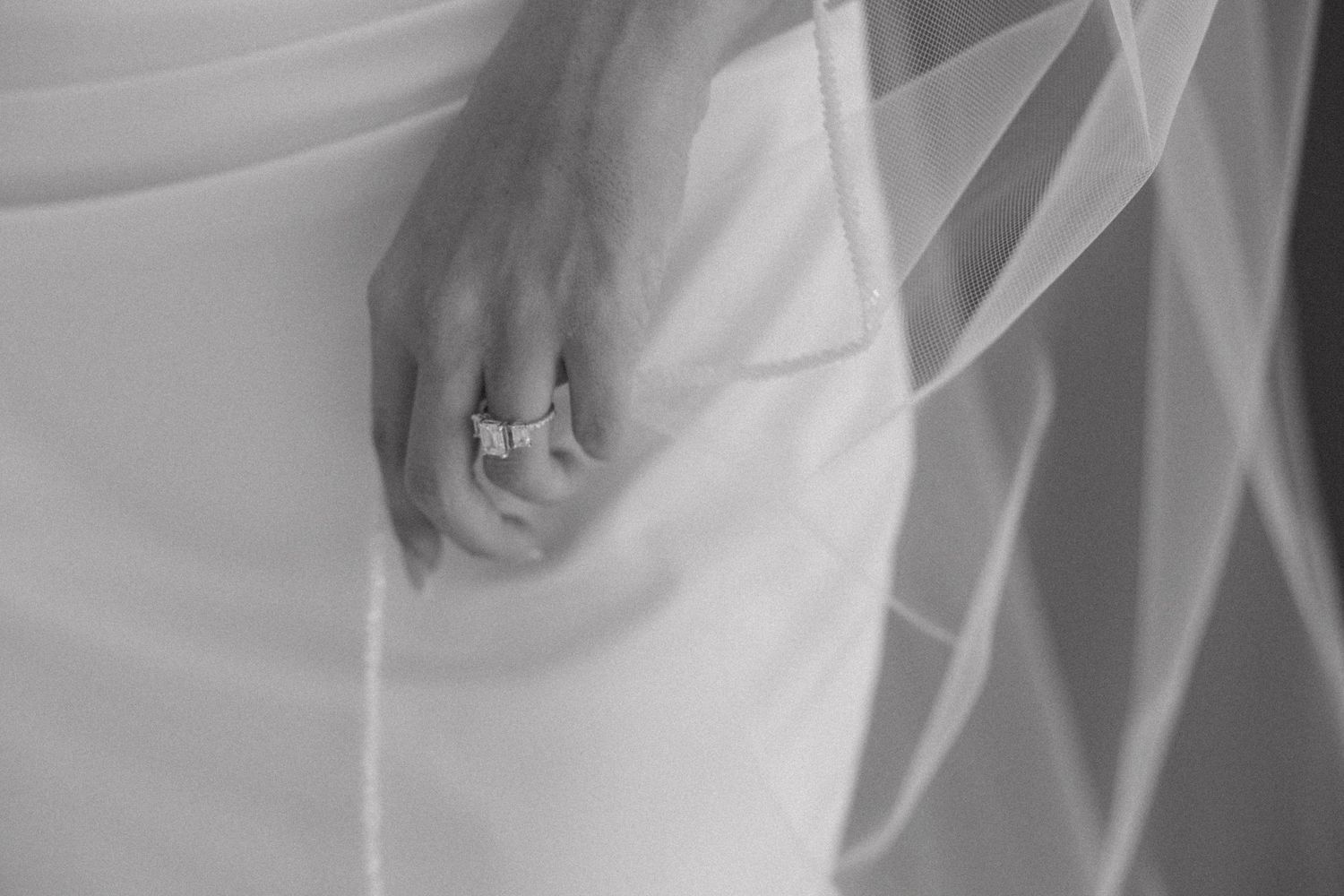Close-up black and white detail of flowing white wedding dress fabric and delicate veil.