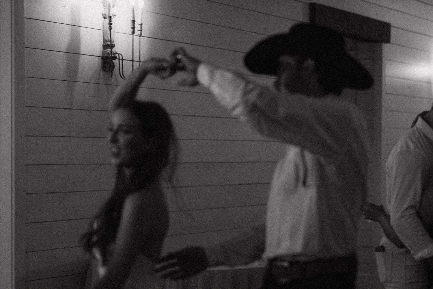A black and white photo of a couple dancing together in an intimate moment at what appears to be a wedding reception.