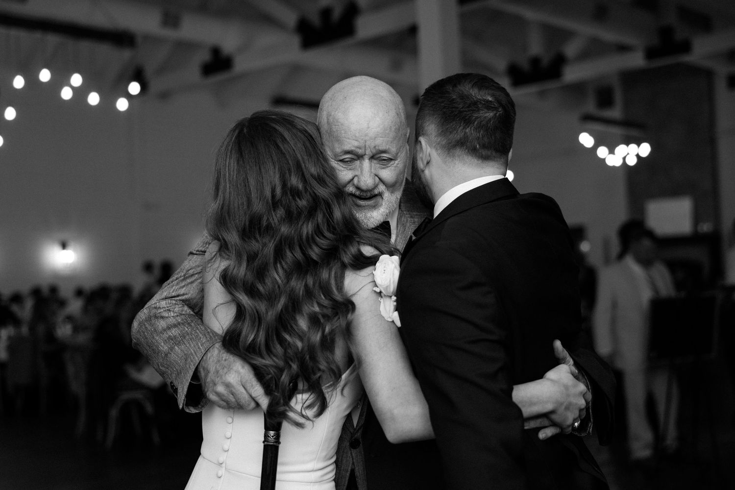 Couples dancing together at a formal event with twinkling lights in the background.