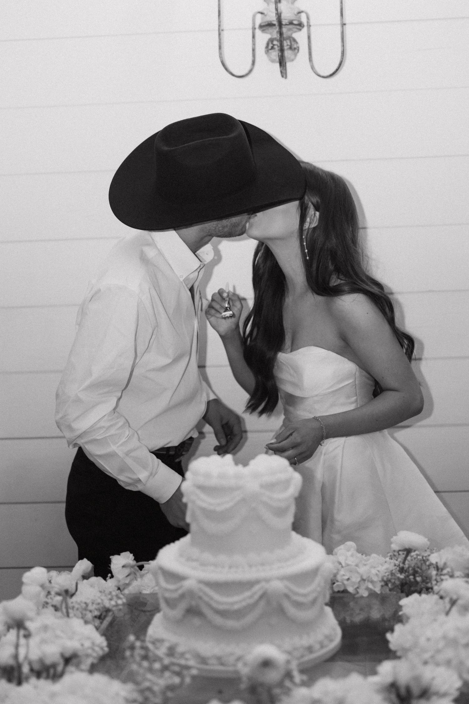 A romantic black and white photo series showing a couple kissing in front of white flowers.