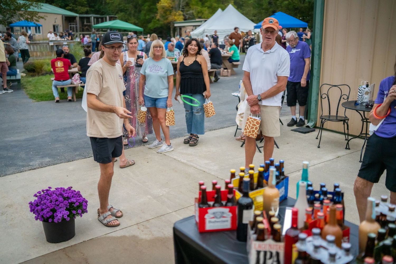 Outdoor beer festival with people browsing IPA and craft beer selections displayed on a table at a community event.