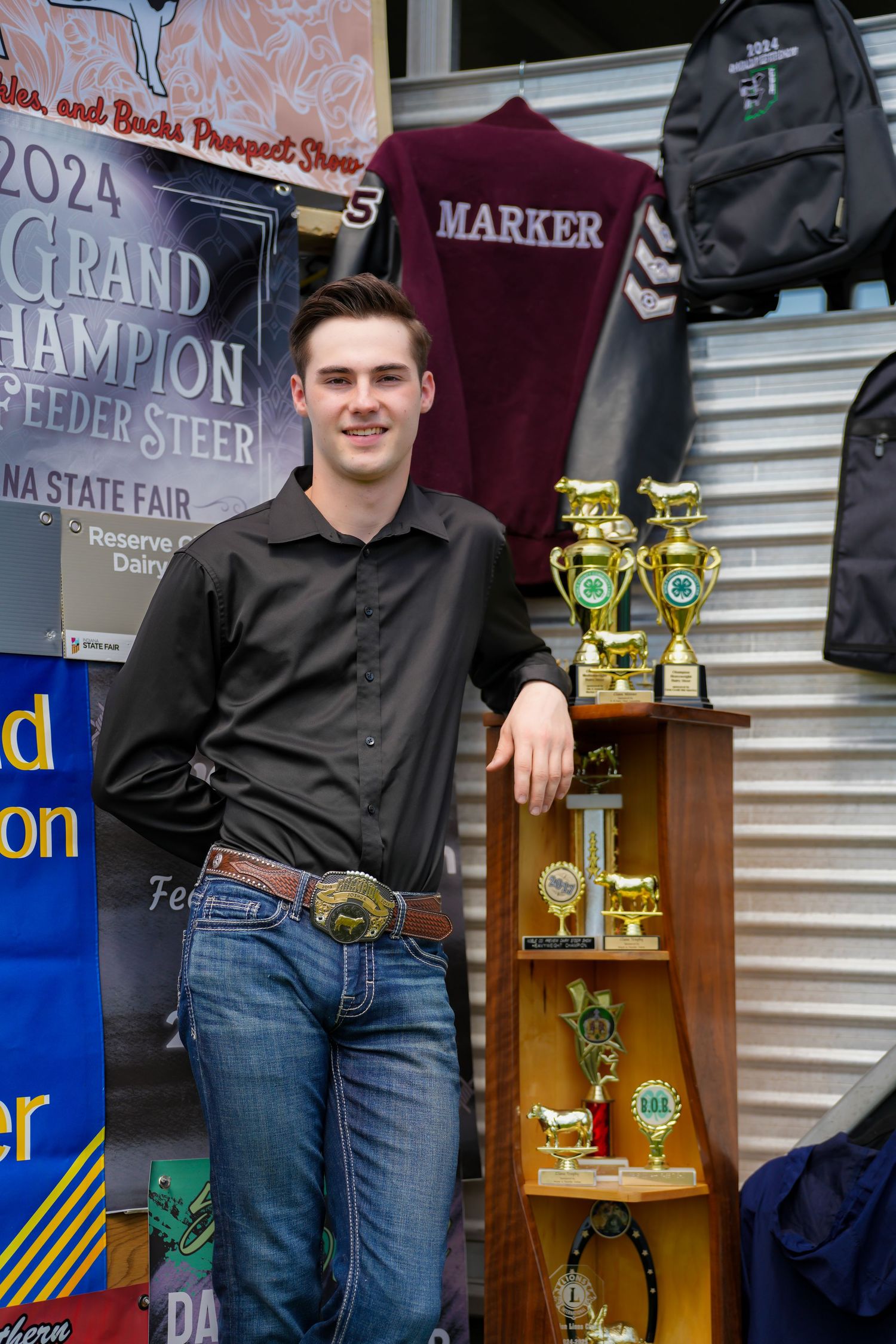 Young man posing with Grand Champion Feeder Steer trophies at Indiana State Fair 2024.
