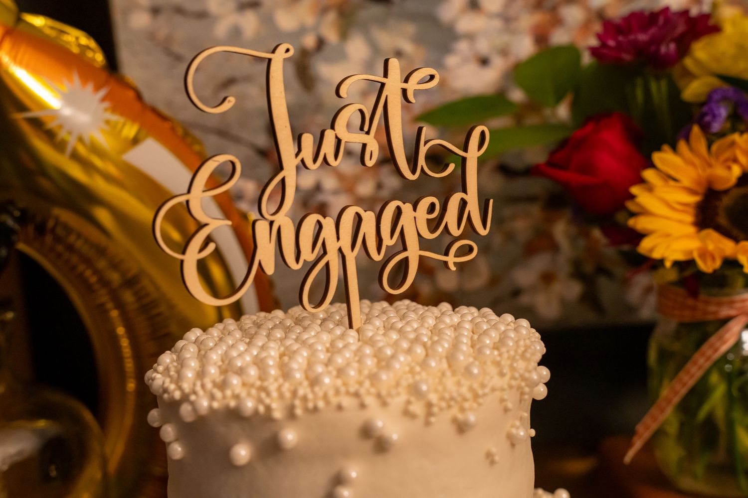 White engagement cake with pearl details and a wooden Just Engaged cake topper.