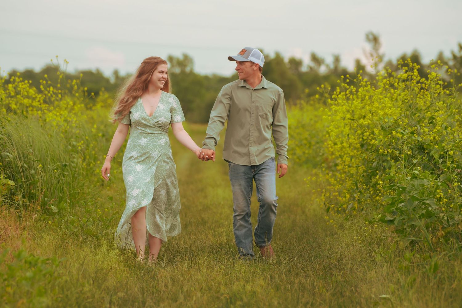 Happy couple walking hand in hand through a vibrant green meadow with wildflowers.