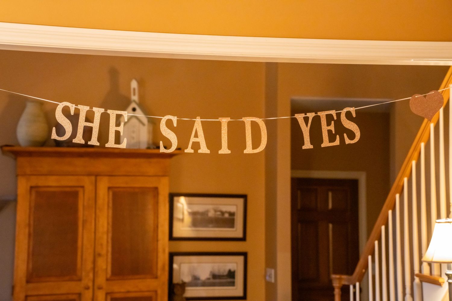 She Said Yes banner hanging on a wall above a wooden cabinet in a home entryway.