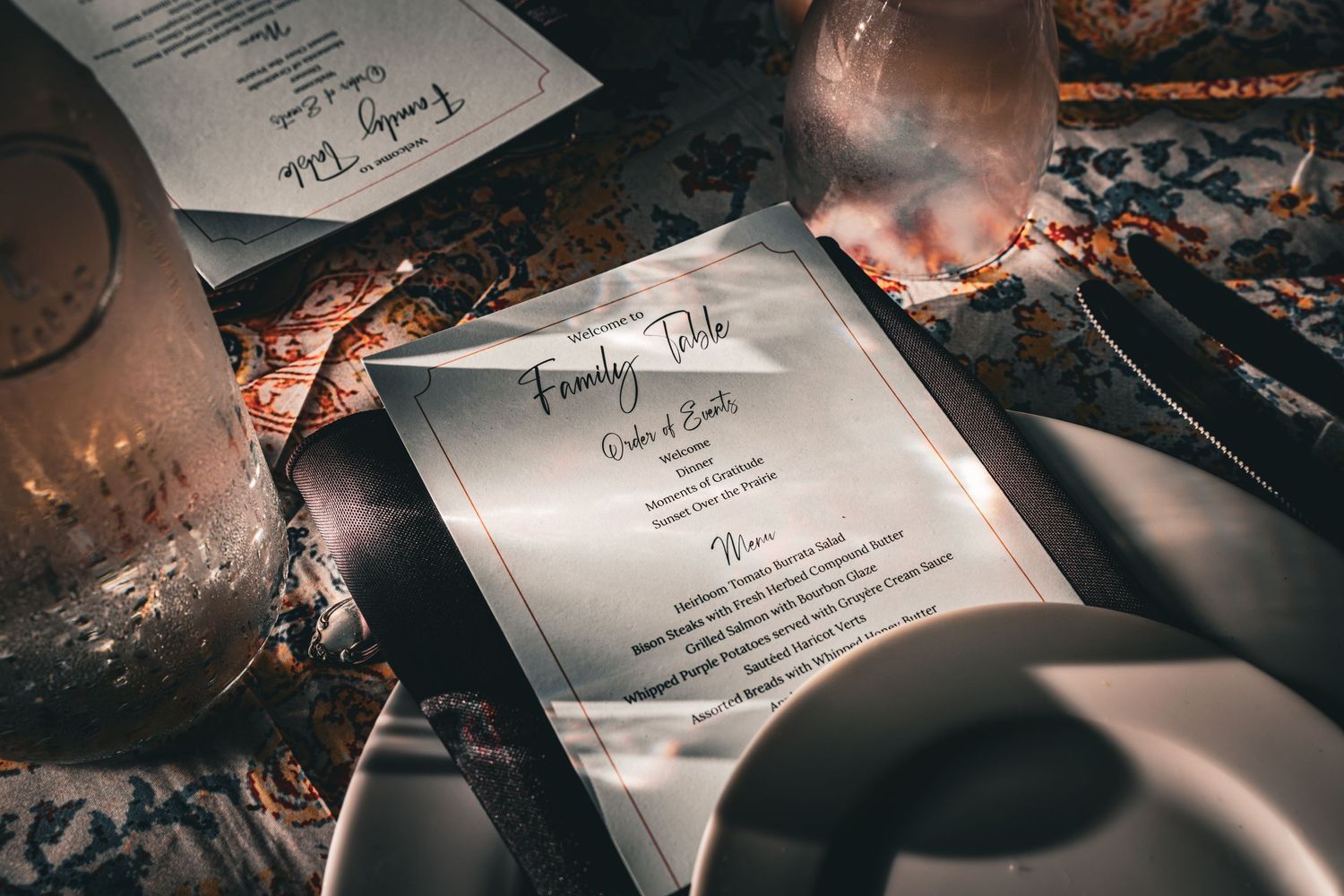 Elegant family table menu card placed on a formal dinner setting with silverware and candles.