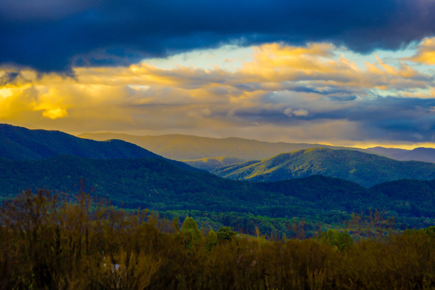 Dramatic sunset over the Blue Ridge Mountains with golden clouds.