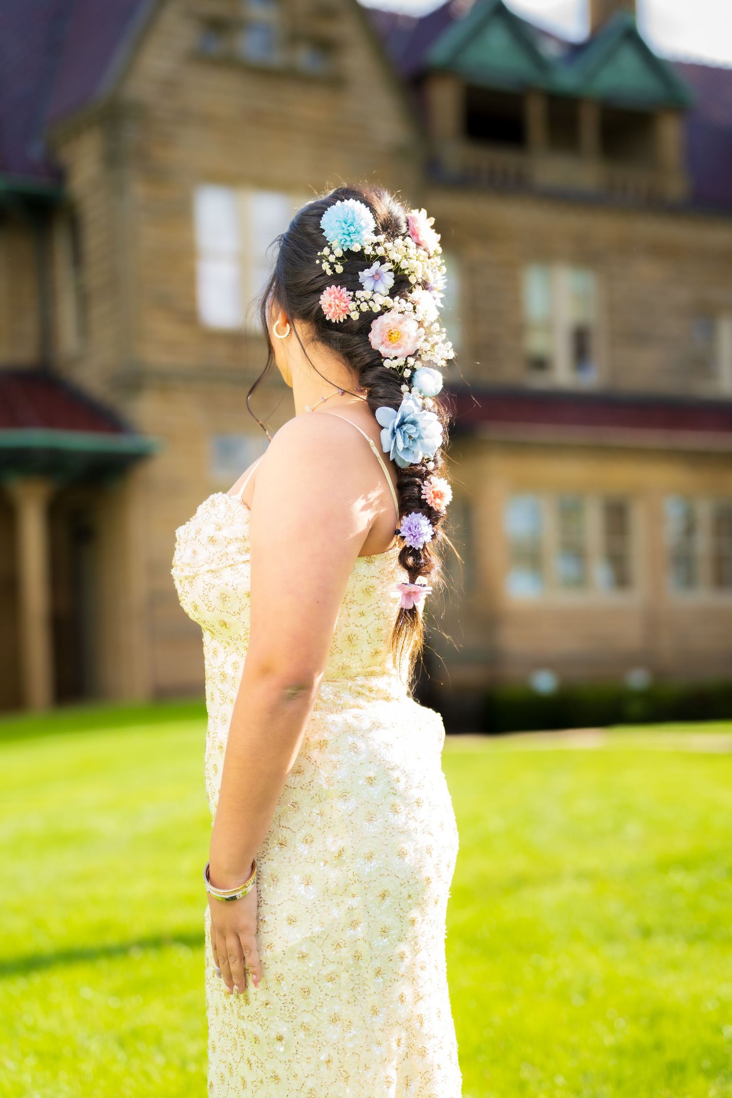 Back view of woman in floral dress with colorful flowers braided in long hair.