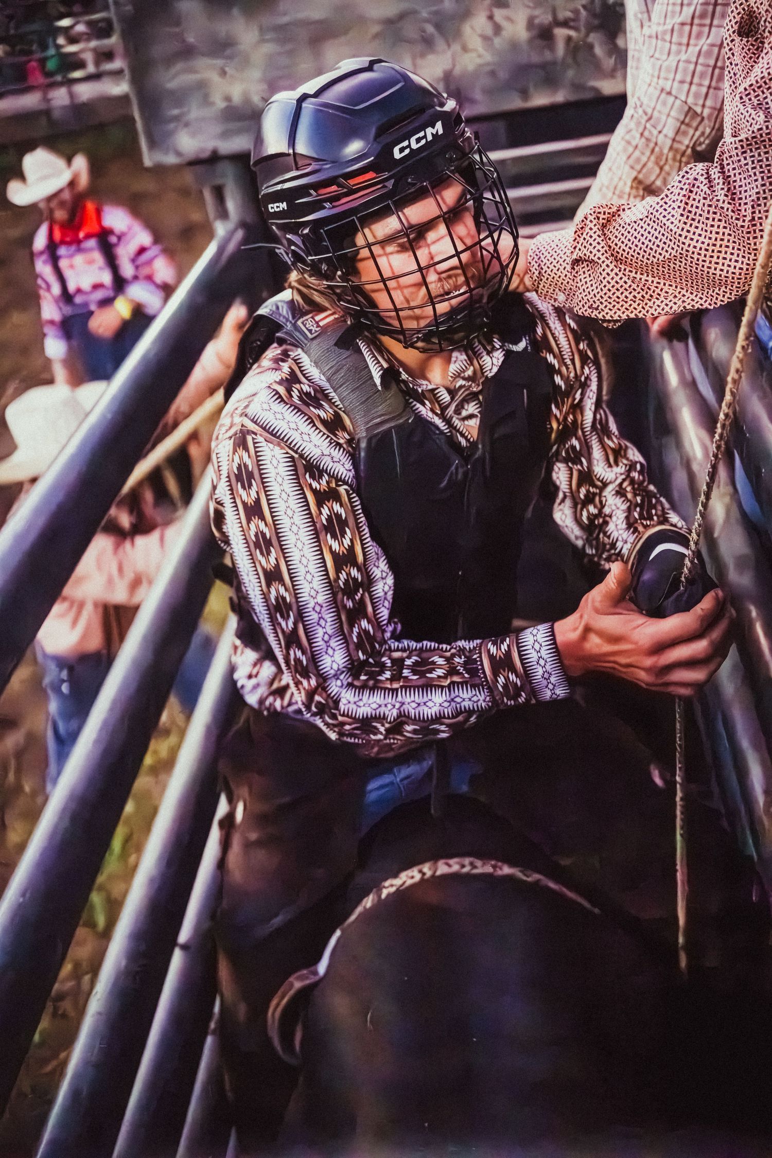 A young bull rider in a CCM helmet sits atop a bull in the chute preparing for a rodeo ride.