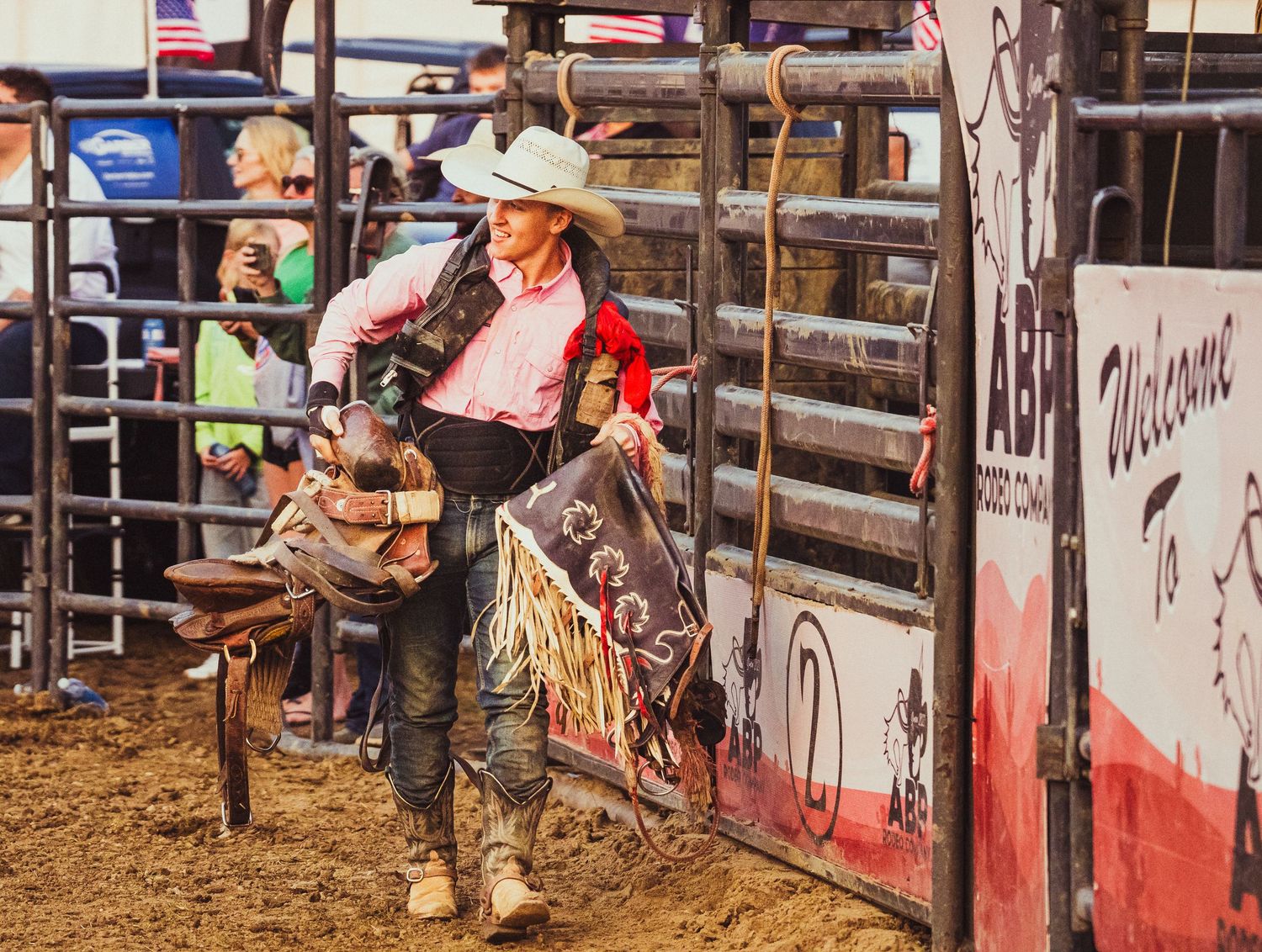 Cowboy in white hat and chaps prepares at rodeo chute during a bull riding competition at a Western rodeo event.