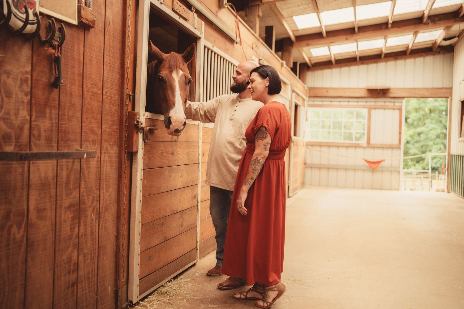 Couple sharing a tender moment with a horse in a rustic wooden stable barn.