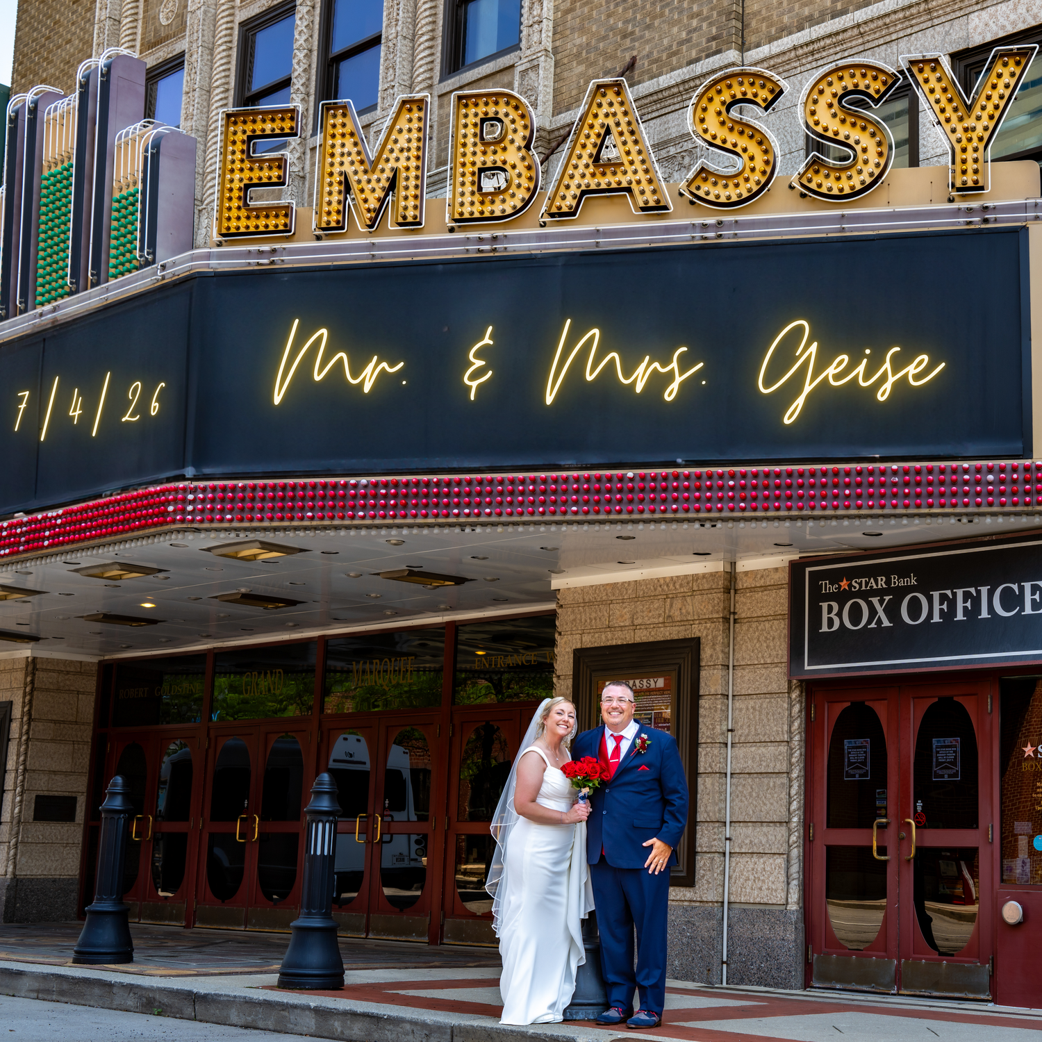Mr. & Mrs. Geise pose outside Embassy Theatre marquee on their wedding day, 7/4/26.
