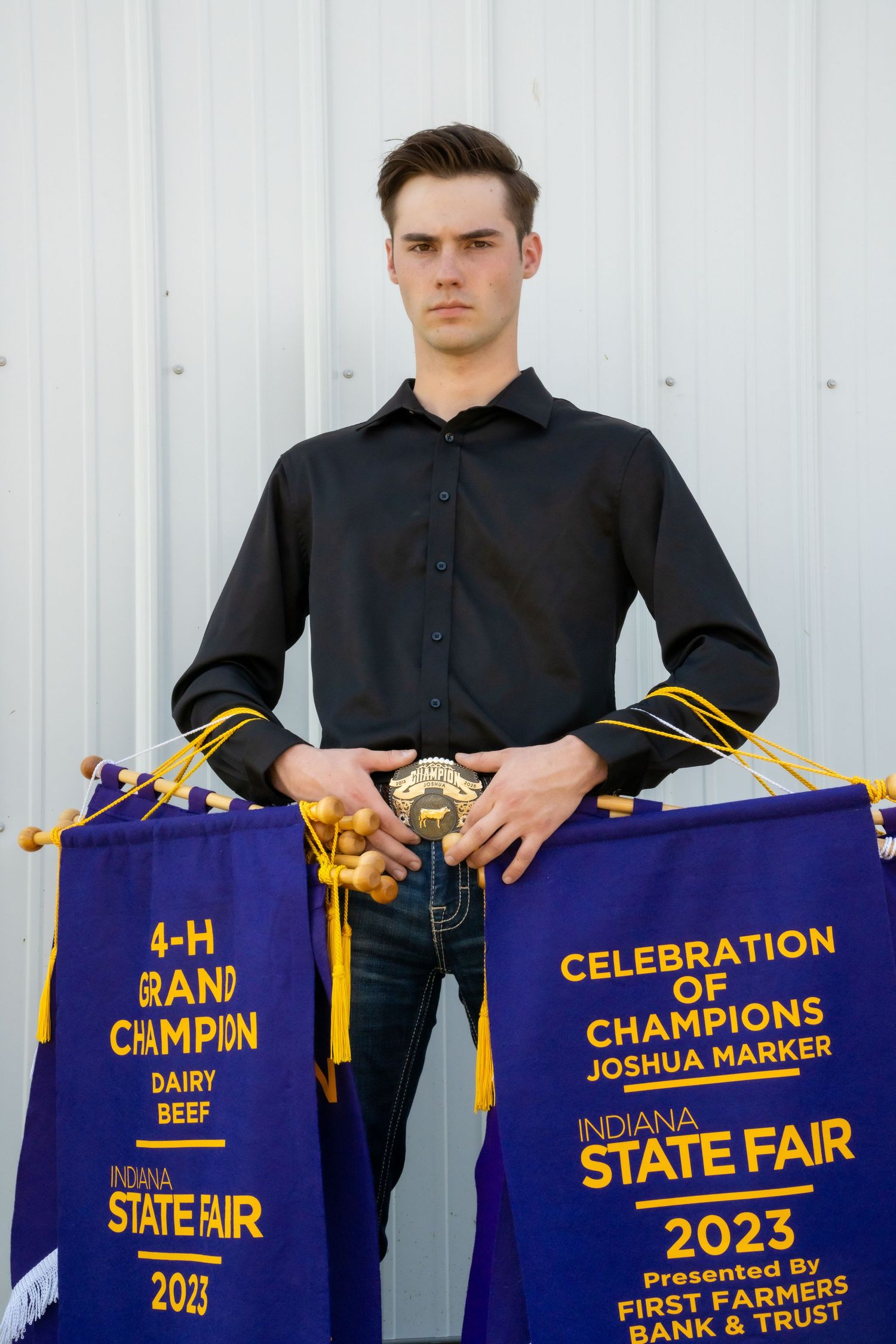Young man holding 4-H Grand Champion Dairy Beef and Celebration of Champions Indiana State Fair 2023 banners.