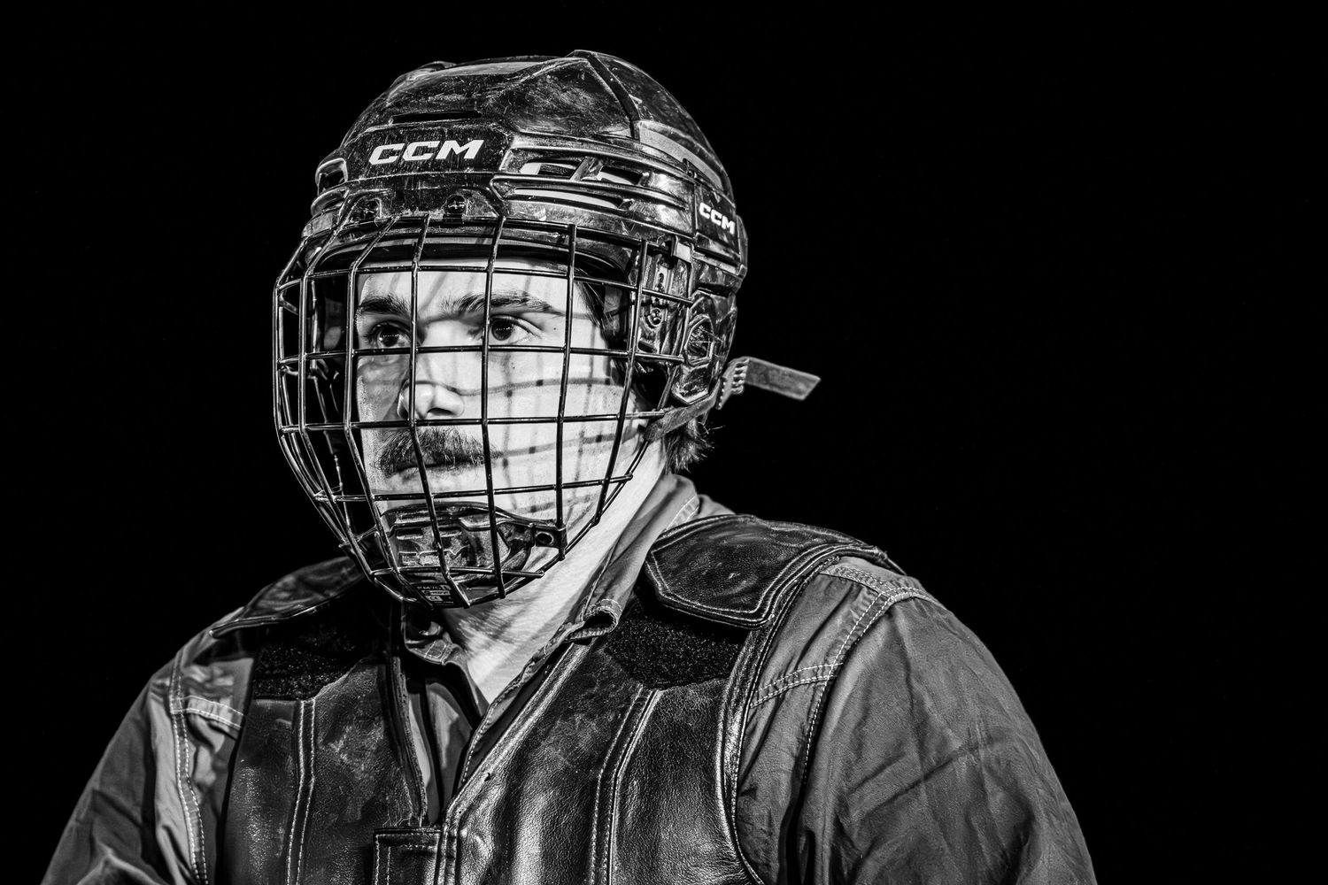 Black and white portrait of a hockey player wearing a CCM helmet with cage face guard and protective gear.