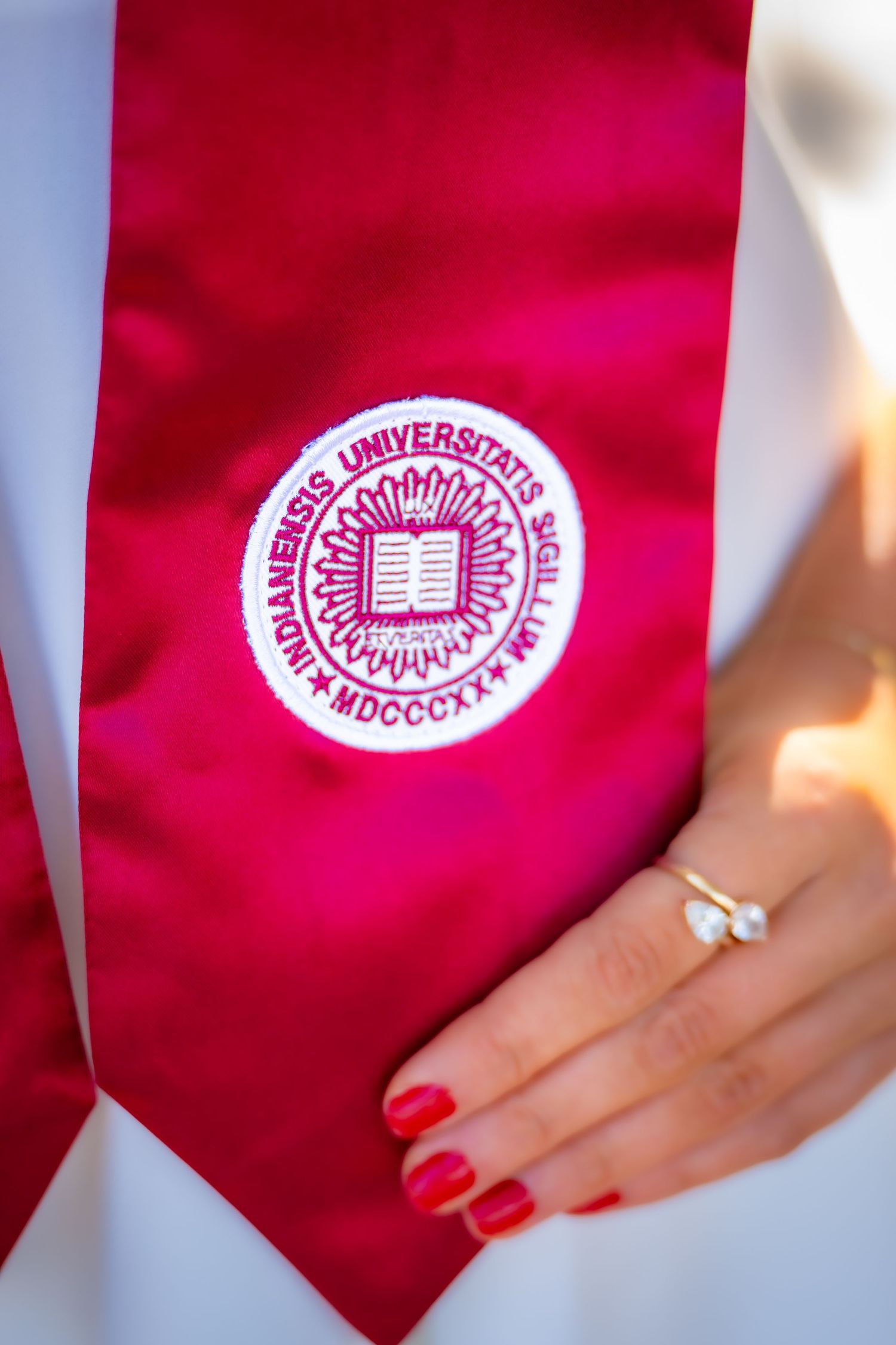 Close-up of crimson Indiana University graduation stole with official university seal and ring.