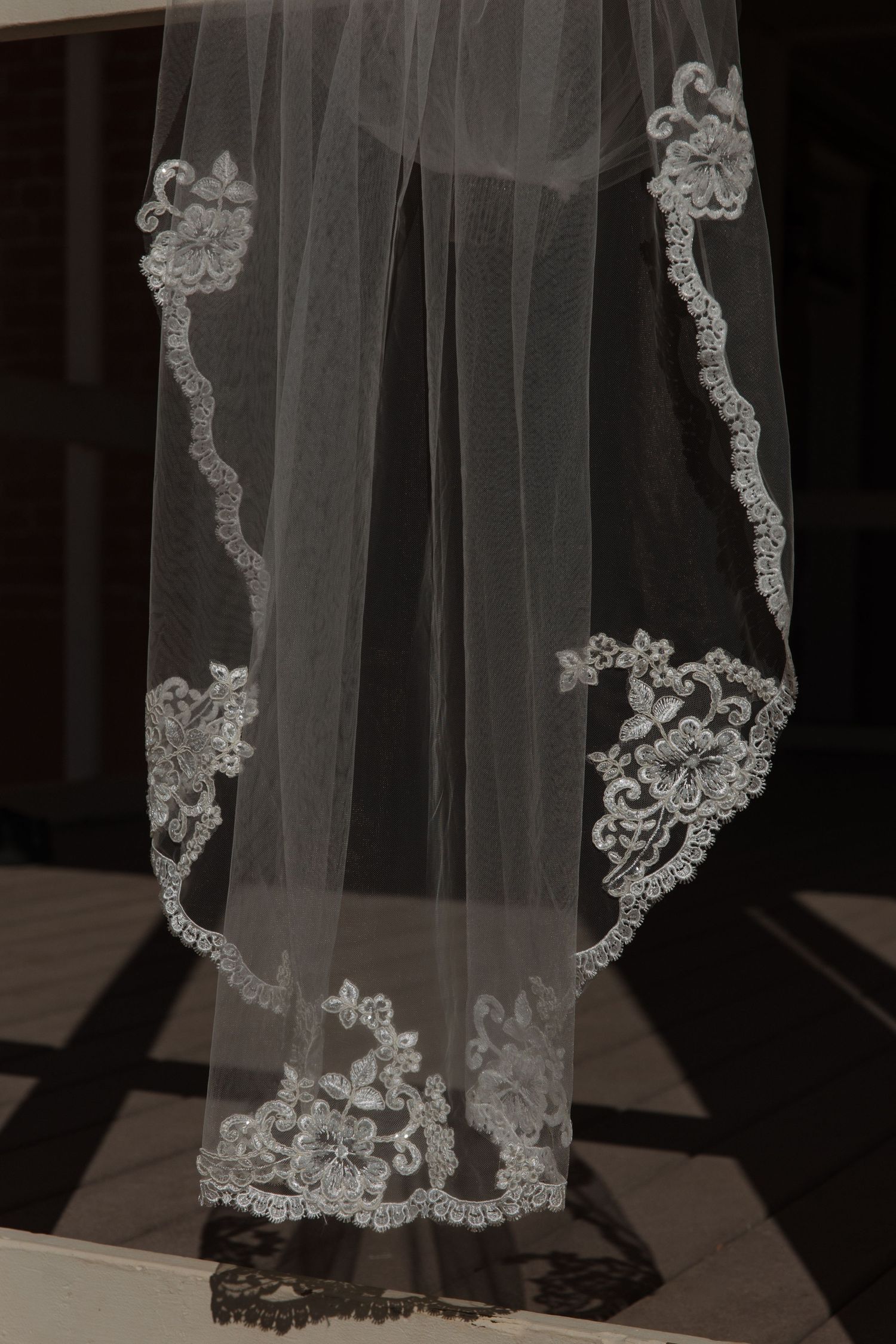 Elegant white bridal veil with intricate lace floral embroidery along the scalloped edge.