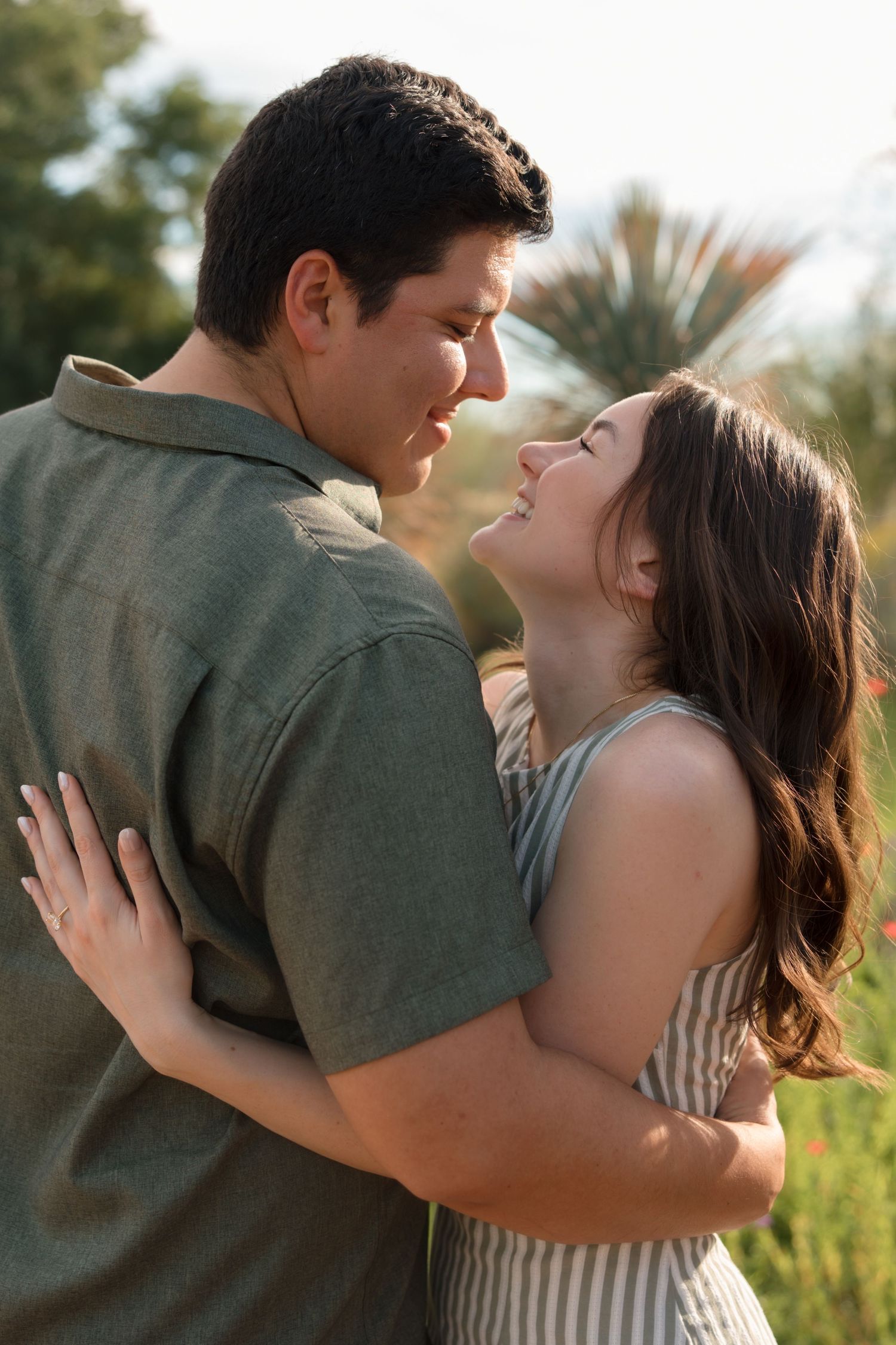 Romantic couple embracing and gazing into each others eyes during golden hour engagement session.