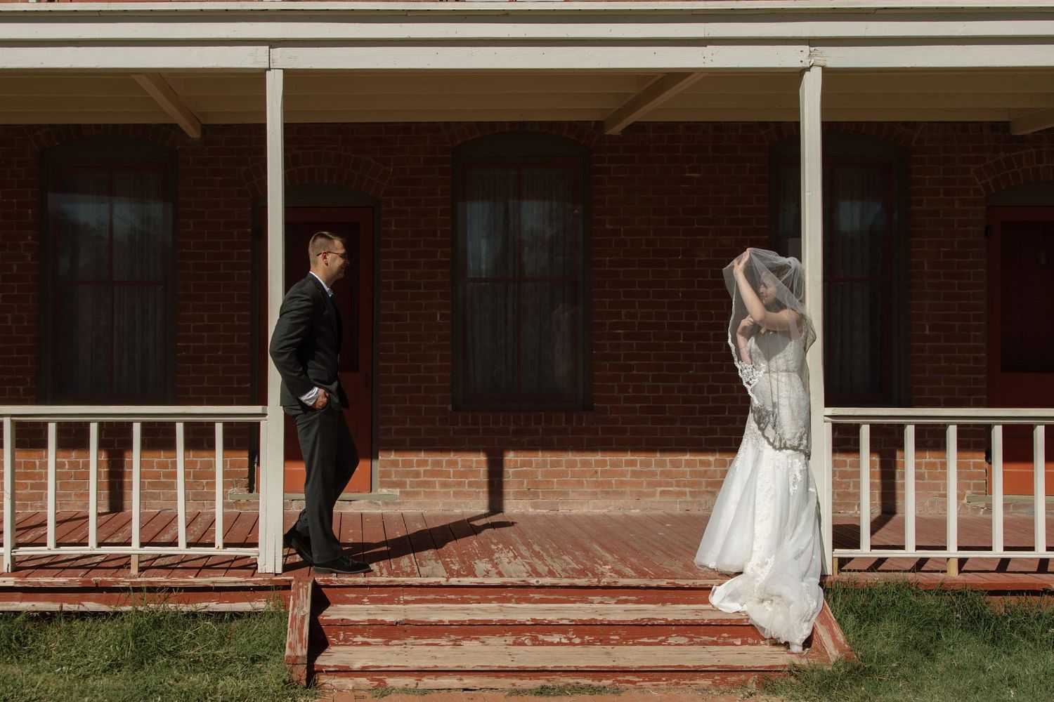Bride and groom share a first look moment on a brick porch of a historic building on their wedding day.