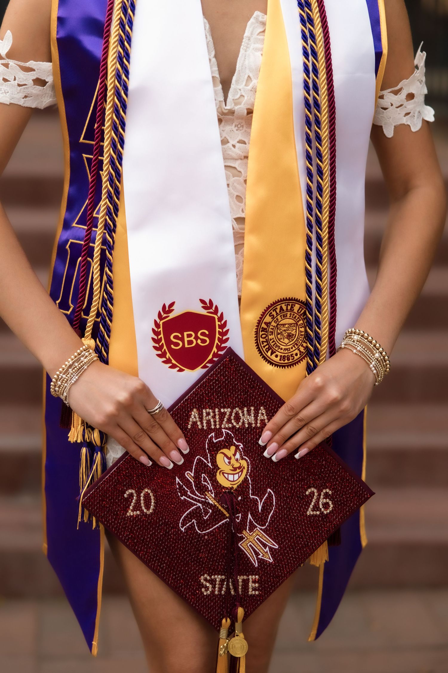 Close-up of Arizona State University graduation regalia including SBS stole and decorated maroon cap reading Arizona State 2026.