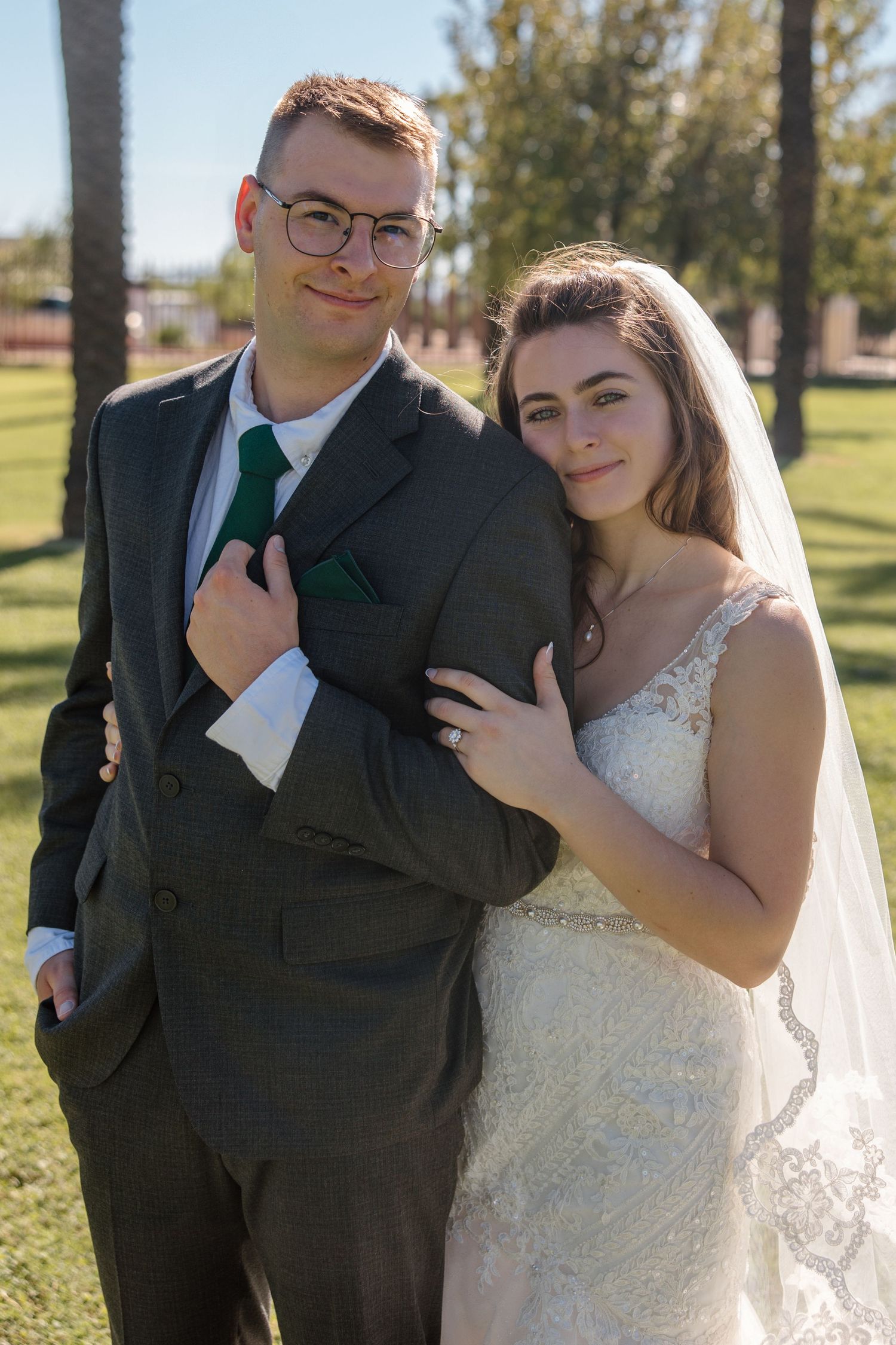 Bride and groom pose together outdoors in park setting on their wedding day.