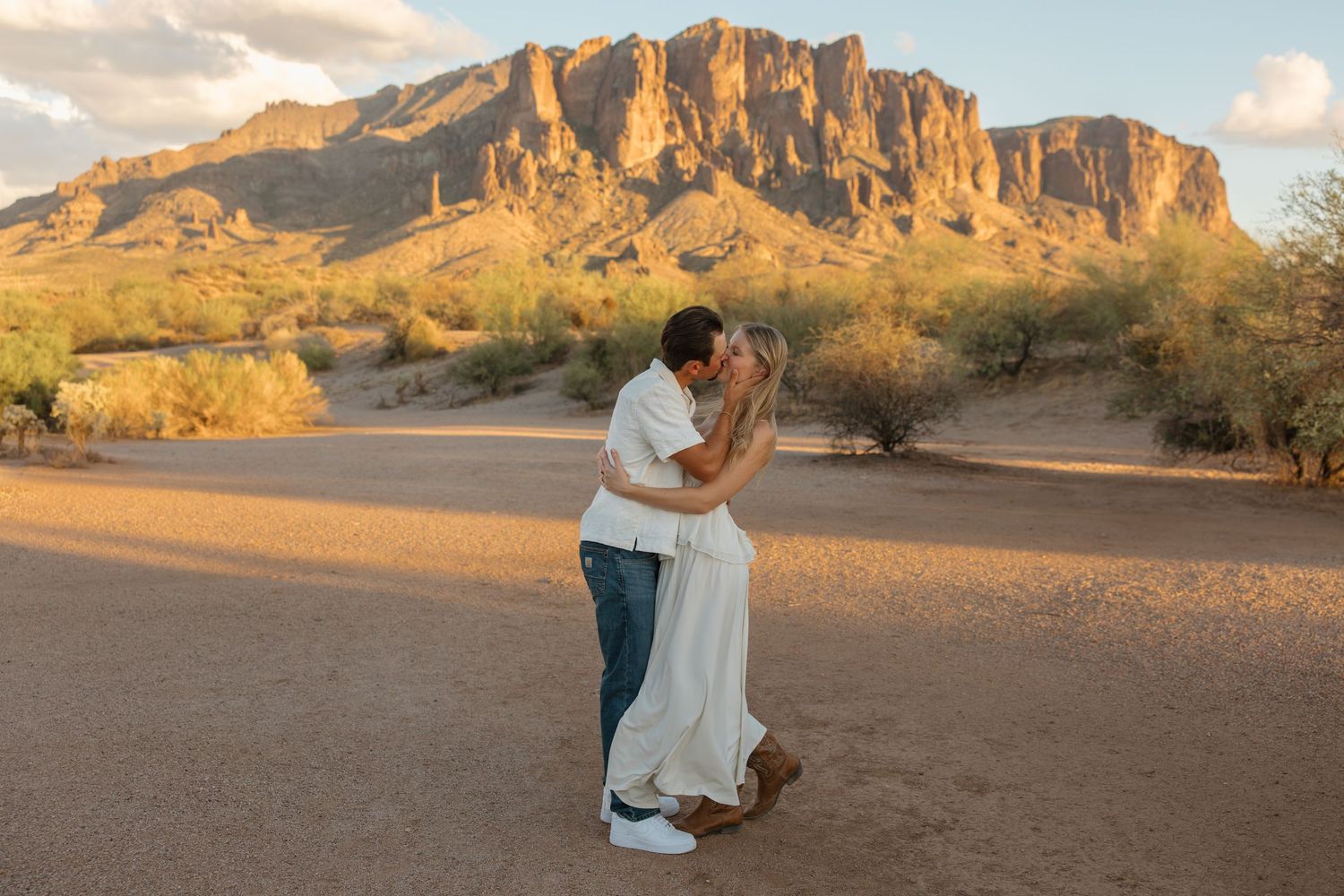 Couple kissing at sunset in the Arizona desert with Superstition Mountains in the background.
