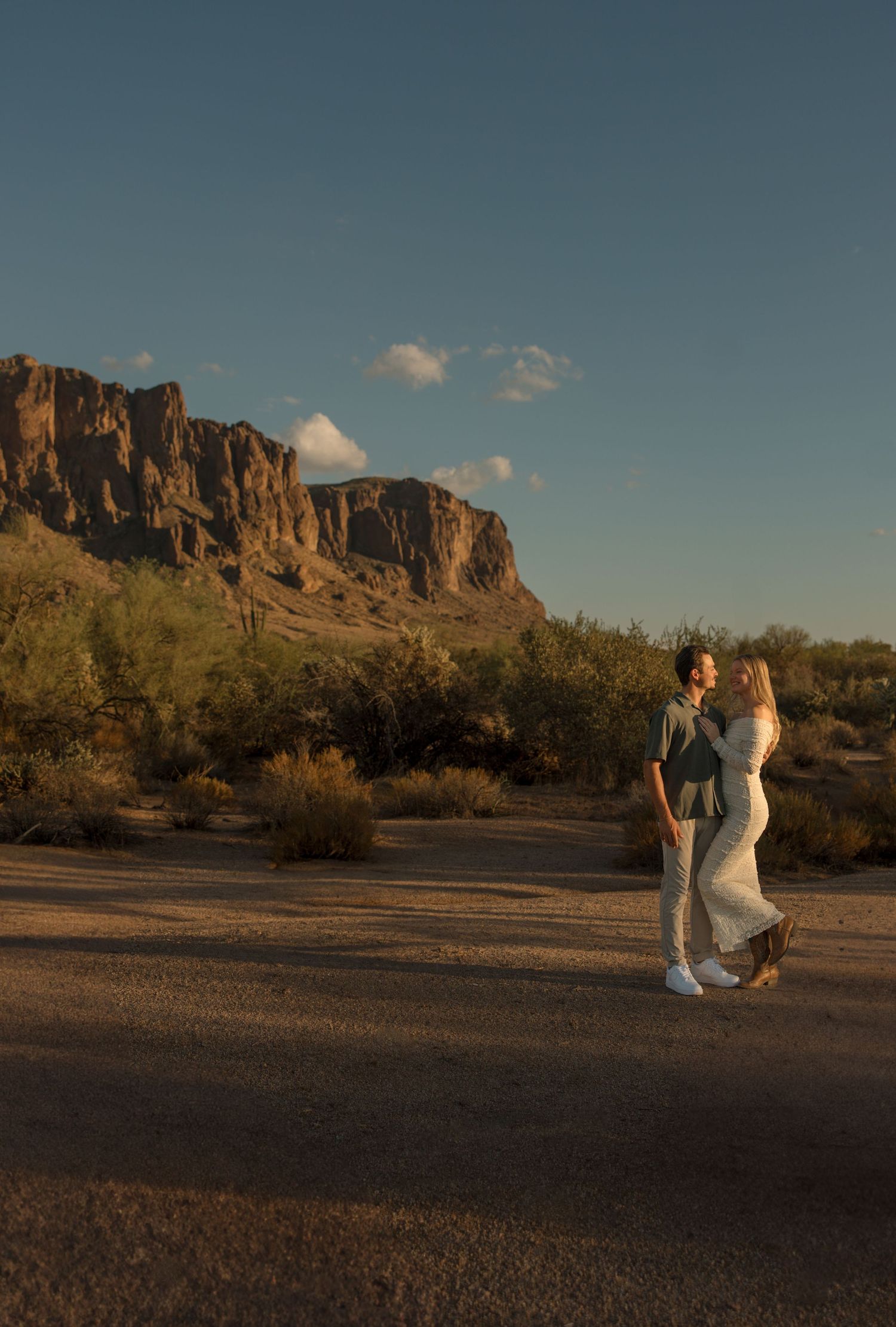 Couple embracing at golden hour in Arizona desert with Superstition Mountains backdrop.