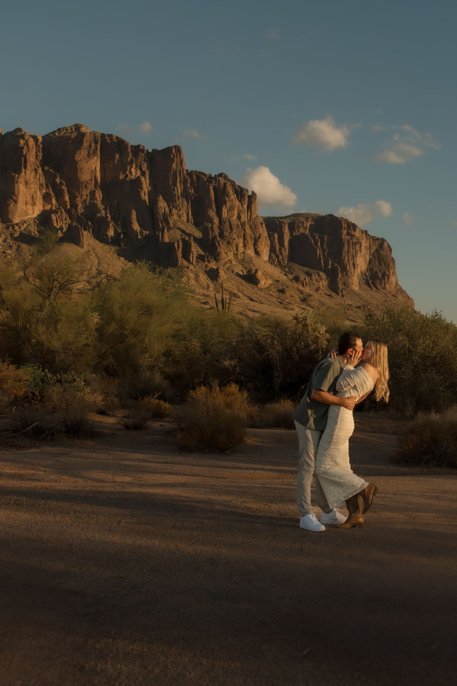 Couple embracing at golden hour in Arizona desert with Superstition Mountains backdrop.