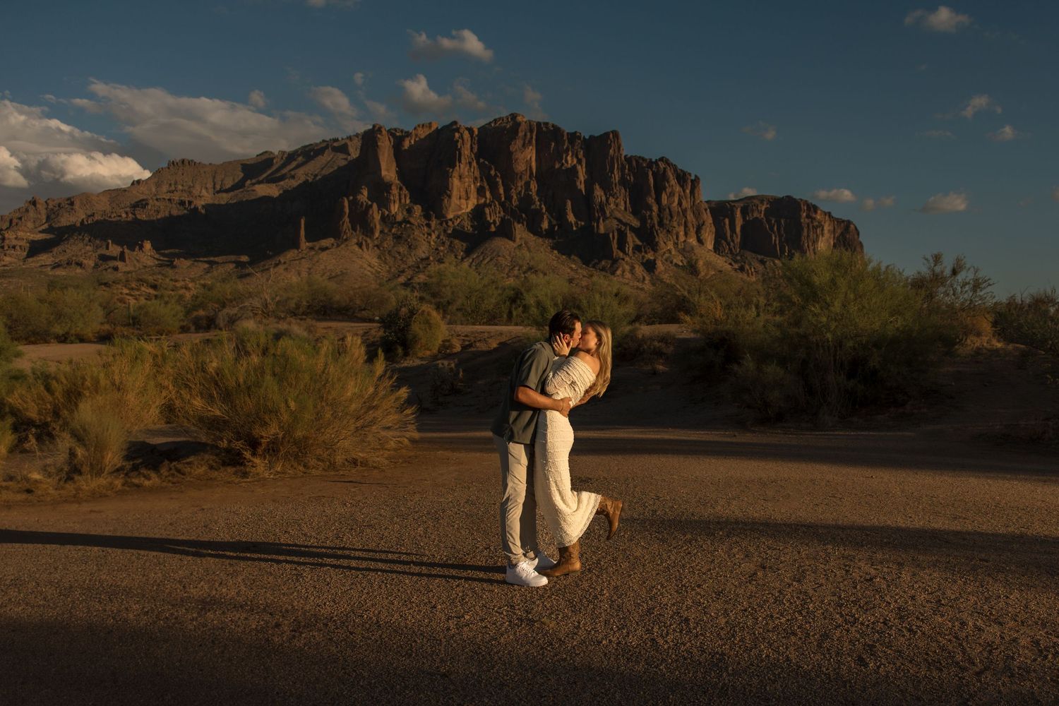 Couple embracing at golden hour with Superstition Mountains backdrop in Arizona desert landscape.