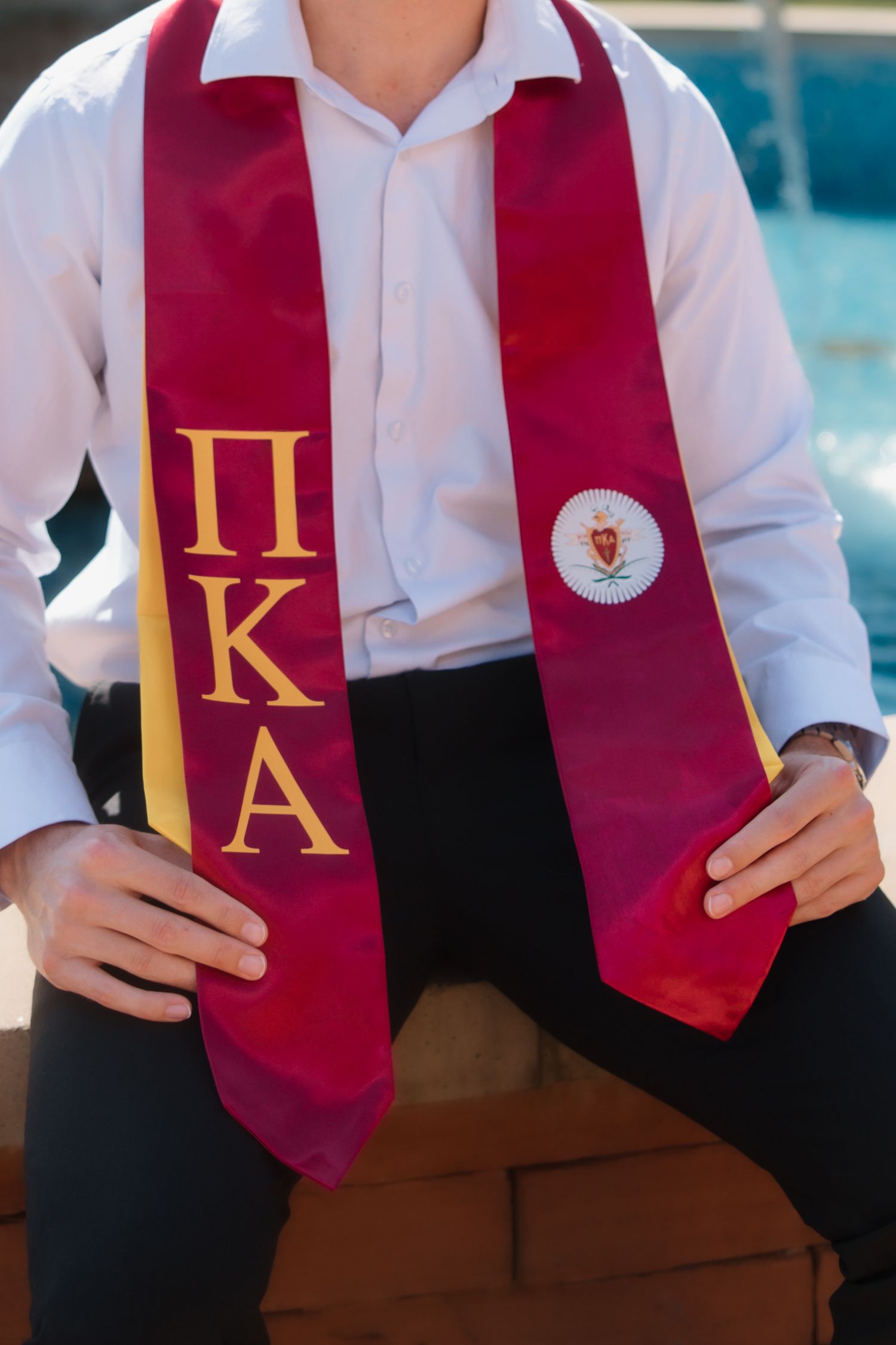 Close-up of Pi Kappa Alpha maroon and gold graduation stole with fraternity crest at ASU.