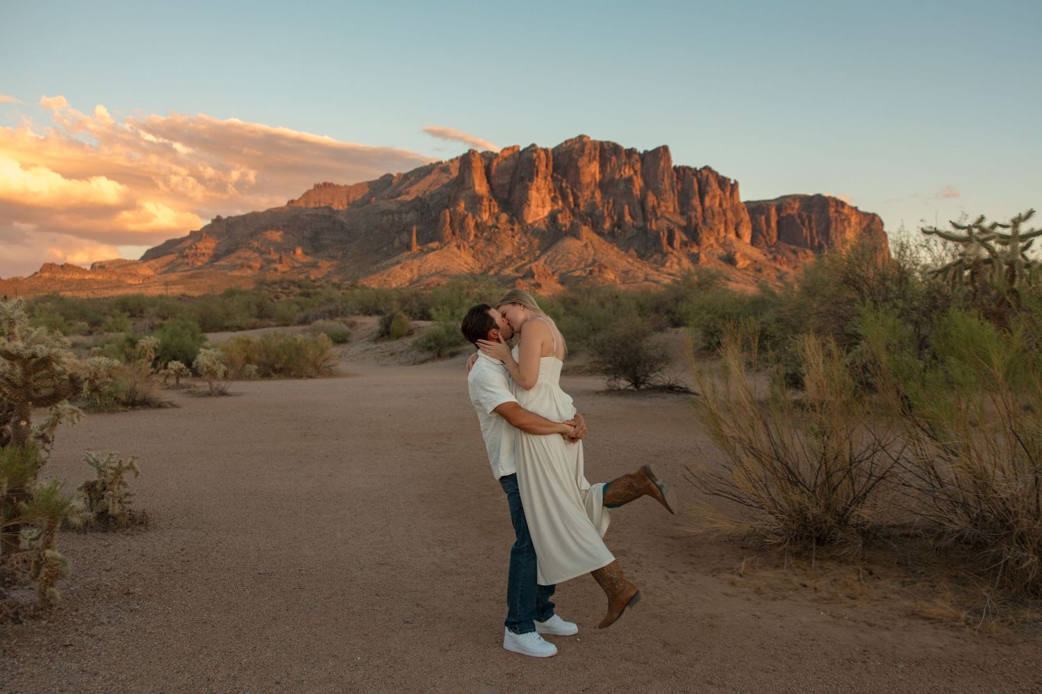 Couple kissing at sunset with Superstition Mountains in the Arizona desert background.