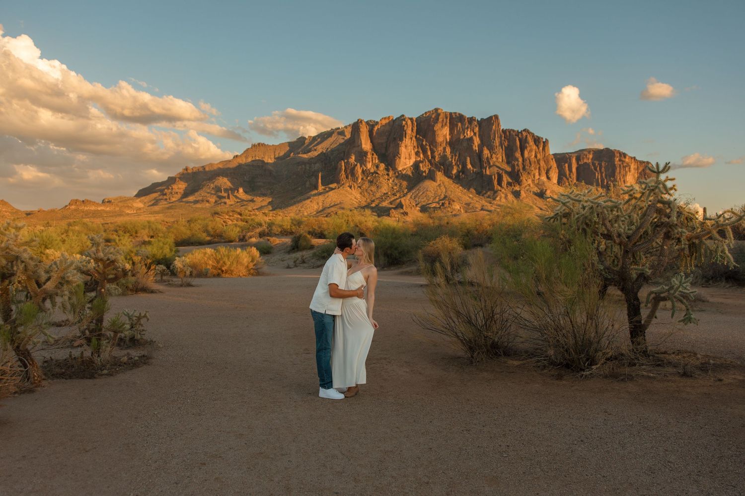 Couple embracing at sunset in Arizona desert with Superstition Mountains backdrop.