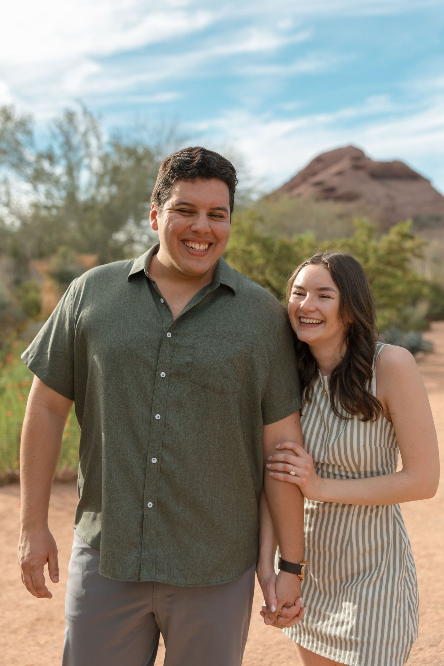 Happy engaged couple smiling and holding hands at Papago Park in Phoenix Arizona on a sunny day.