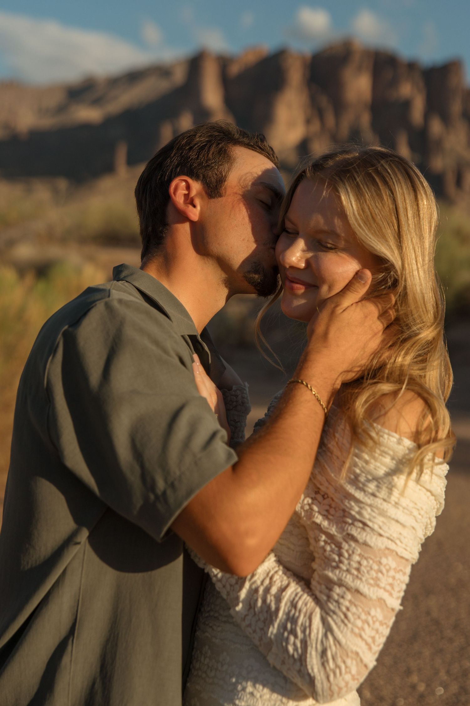 Couple sharing a tender moment at golden hour with desert mountains in the background.