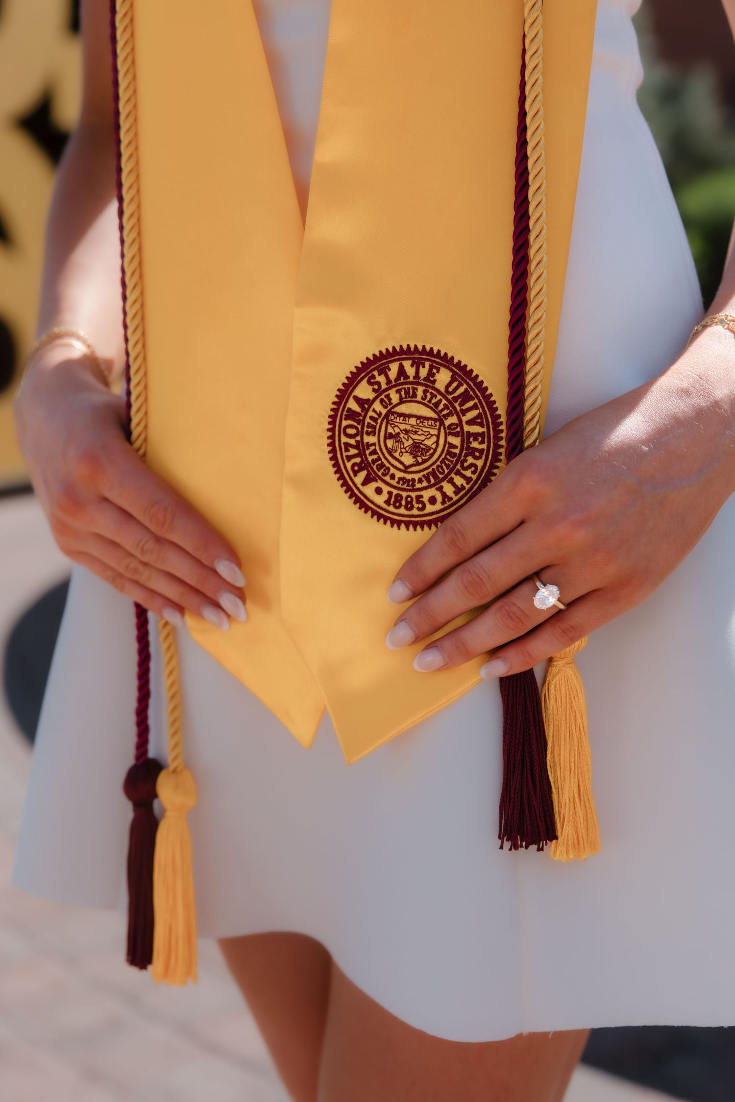 Close-up of ASU gold graduation stole with university seal and maroon tassel held by graduate.
