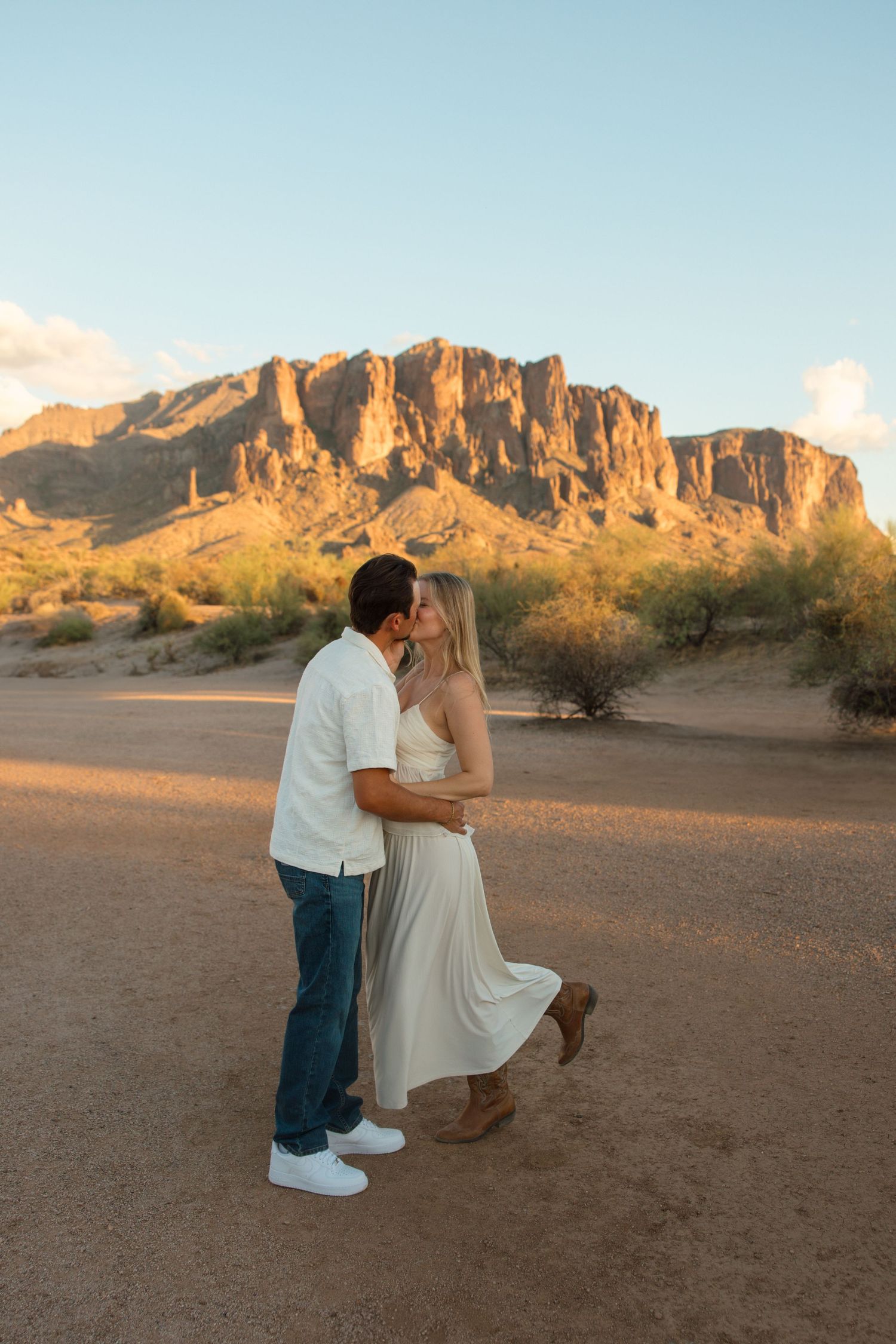 Couple sharing a romantic moment in the desert with Superstition Mountains glowing at golden hour in Arizona.