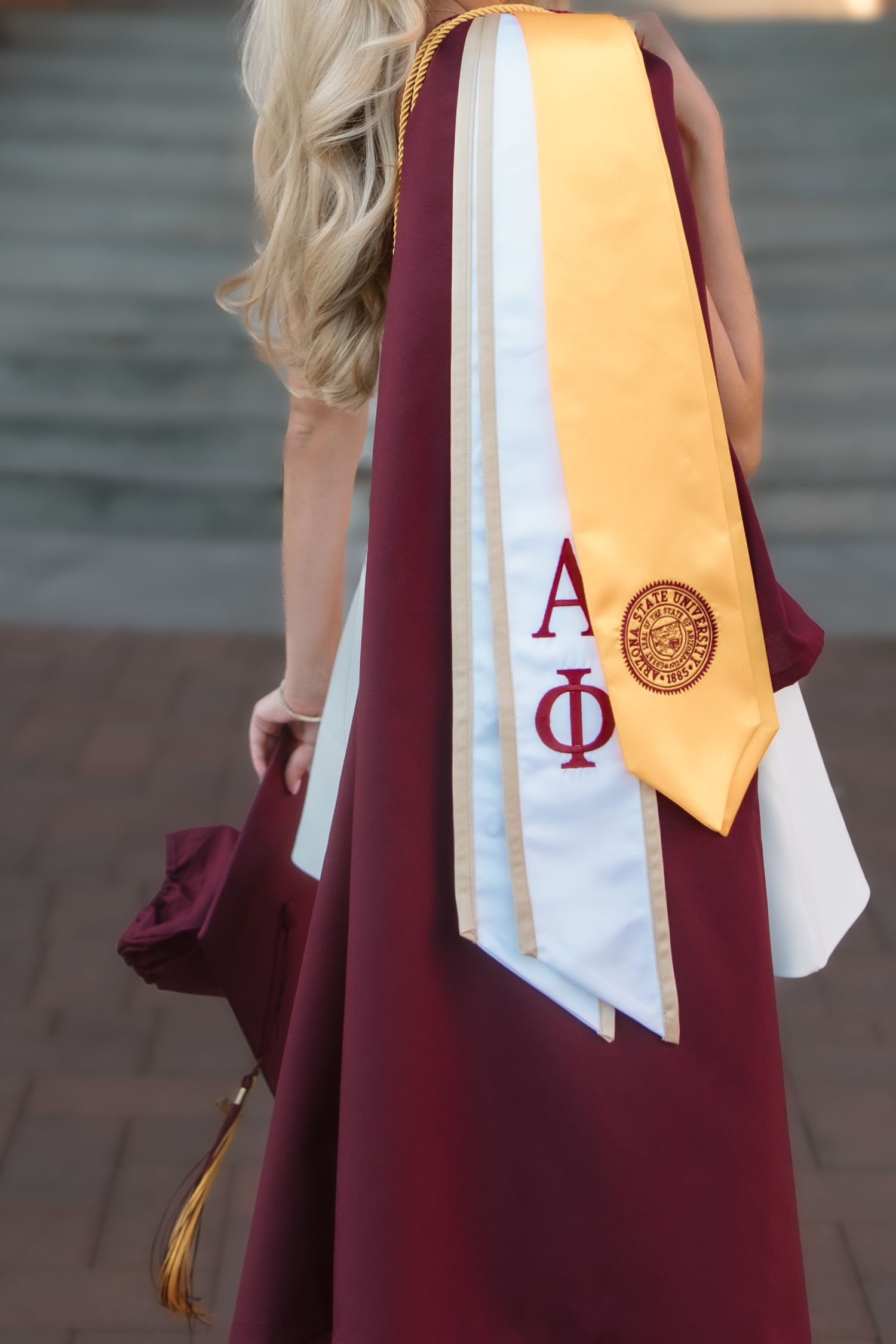 Close-up of Alpha Phi sorority graduation stole with gold ASU honor stole on maroon graduation gown.