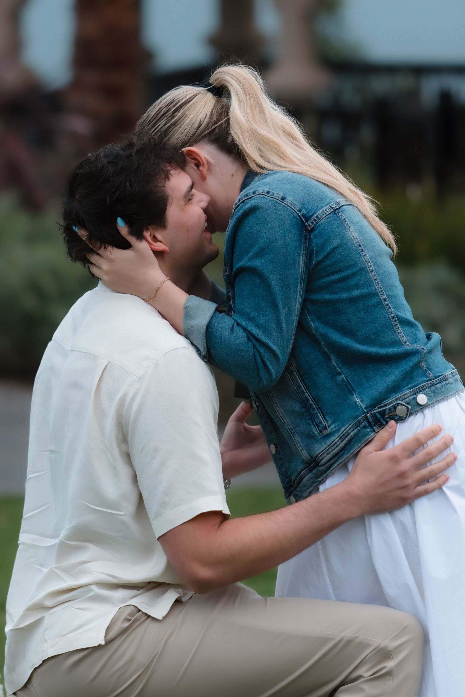 Couple sharing a romantic kiss during an outdoor marriage proposal at a scenic coastal venue.