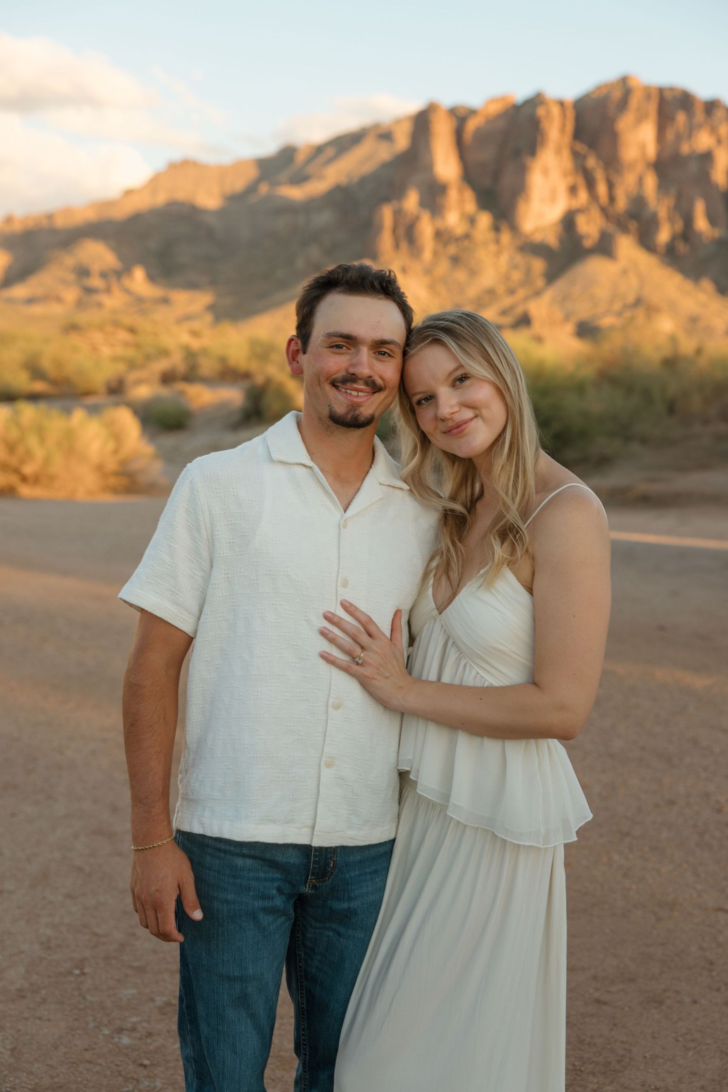 Couple posing together at golden hour in the Arizona desert with Superstition Mountains in the background.