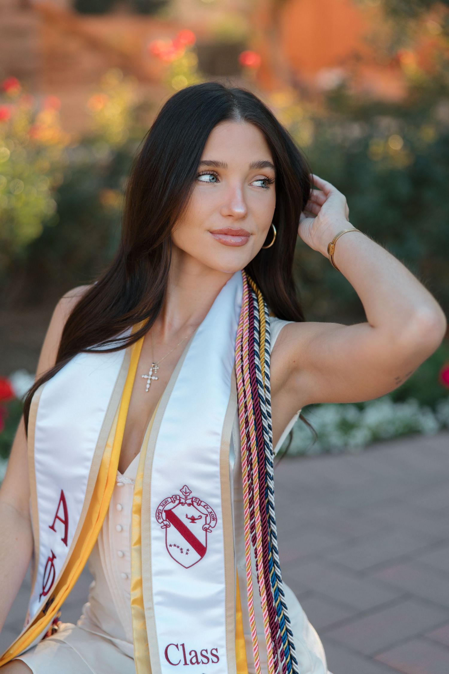 Close-up of brunette graduate wearing Alpha Phi Class of 2025 stole with colorful honor cords.